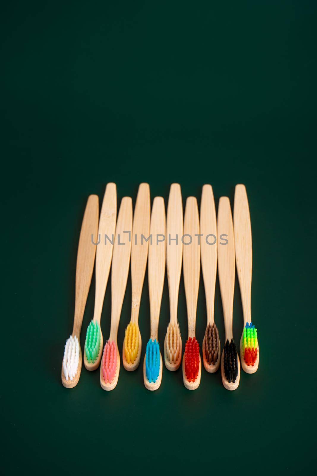 A set of Eco-friendly antibacterial toothbrushes made of bamboo wood on a dark green background. Environmental trends by Try_my_best