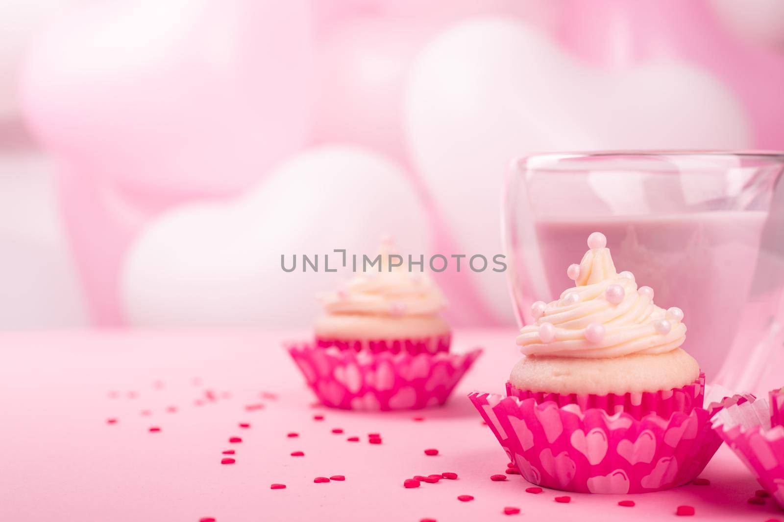 Valentine day love cupcake decorated with cream and hot chocolate on pink heart balloons background with copy space for text