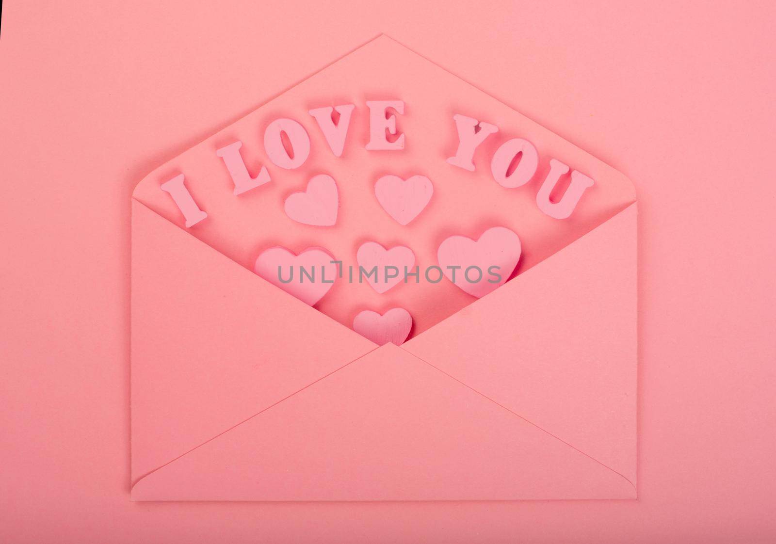 Pink love letter and wooden hearts painted I love you letters on pink background