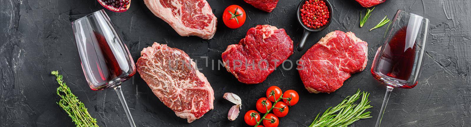Set of various classic, alternative raw meatsteaks with glasses of red wine over black background top view. Big banner size