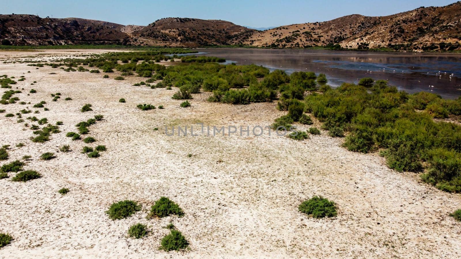aerial drone shoot from side of an old lake - white sands and mountain background also there is short green plants. photo has taken at bafa lake at turkey.