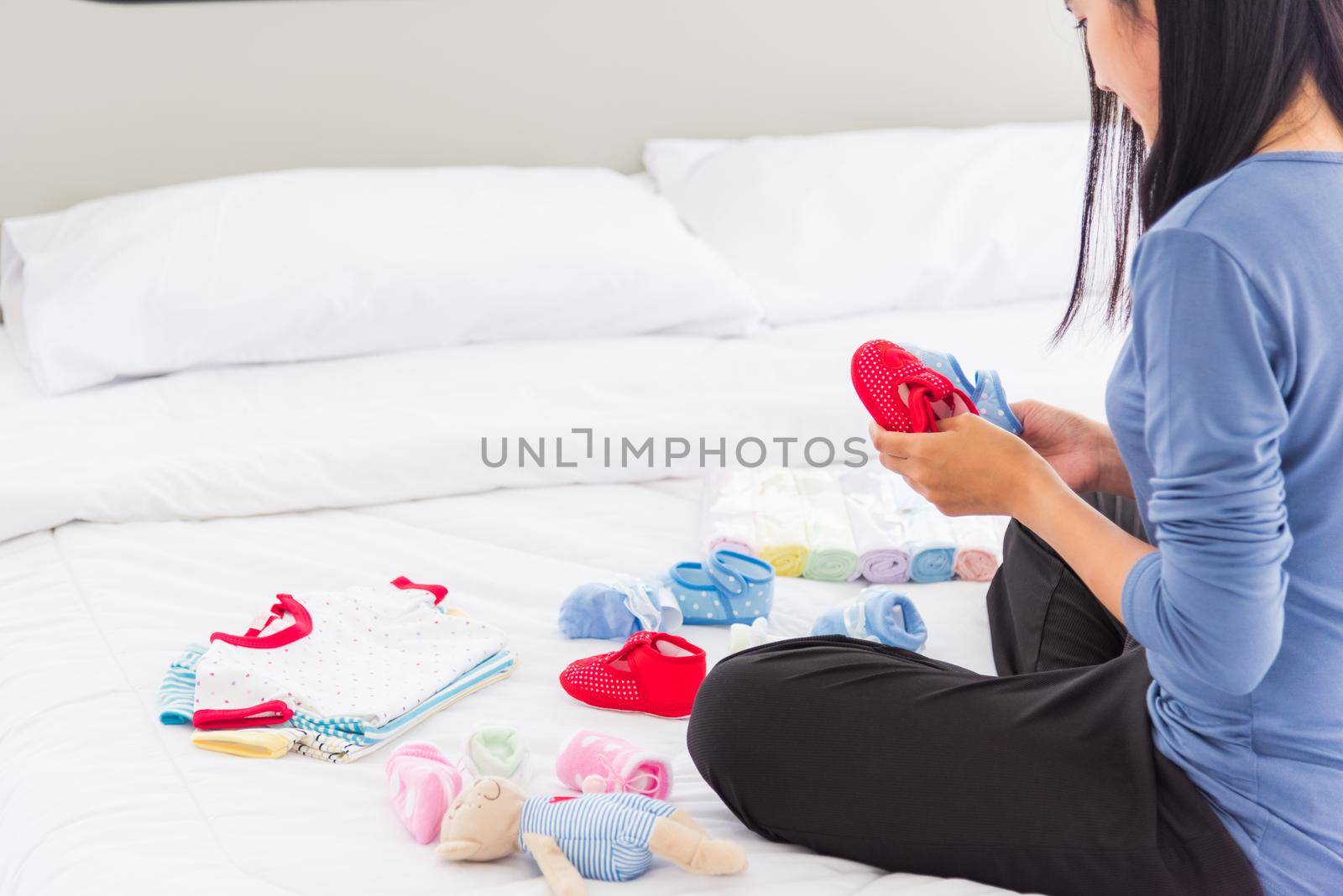 mother preparing baby clothes resting and relaxing on the bed by Sorapop