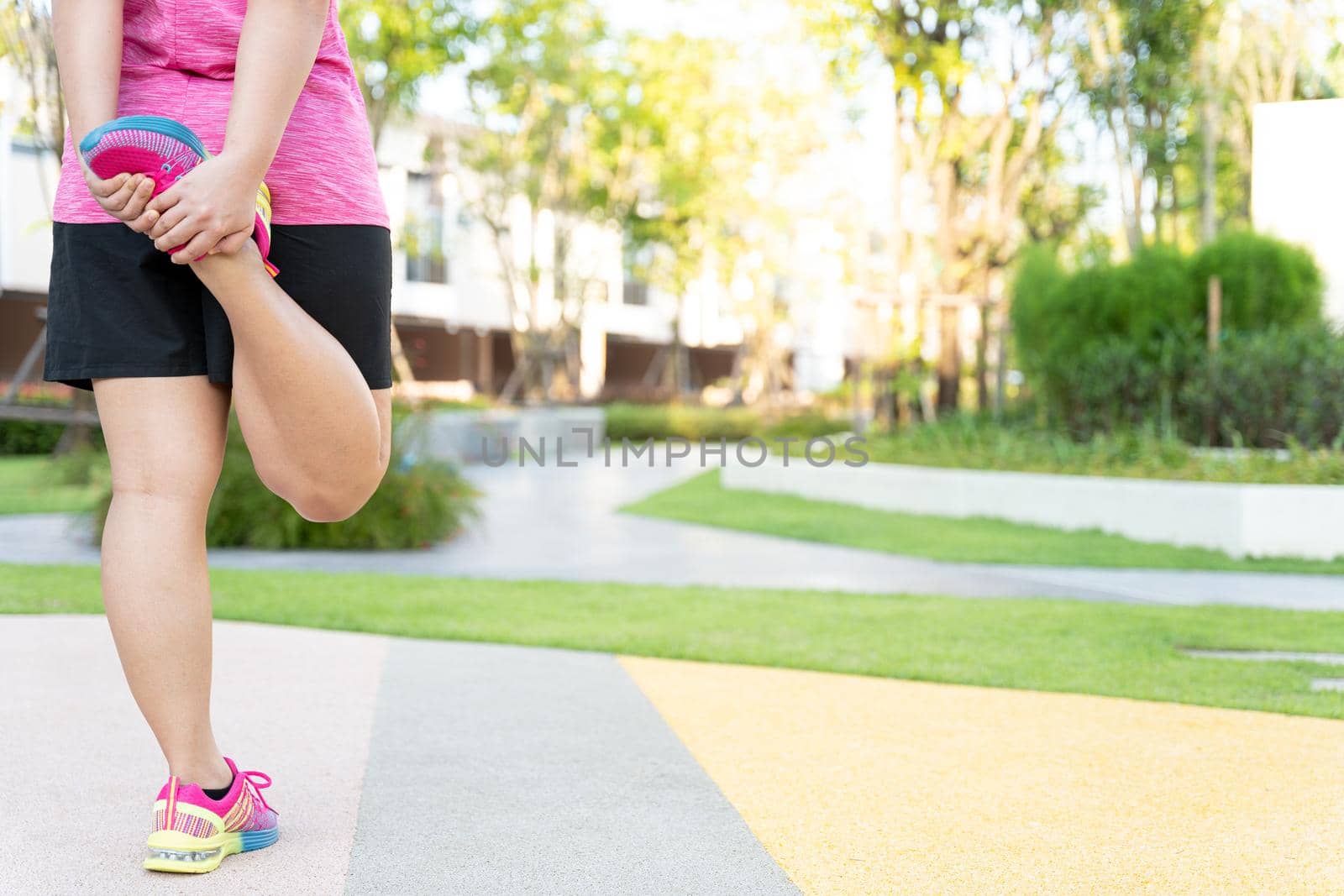 Female fatty runner athlete stretching legs before running in the park. by mikesaran