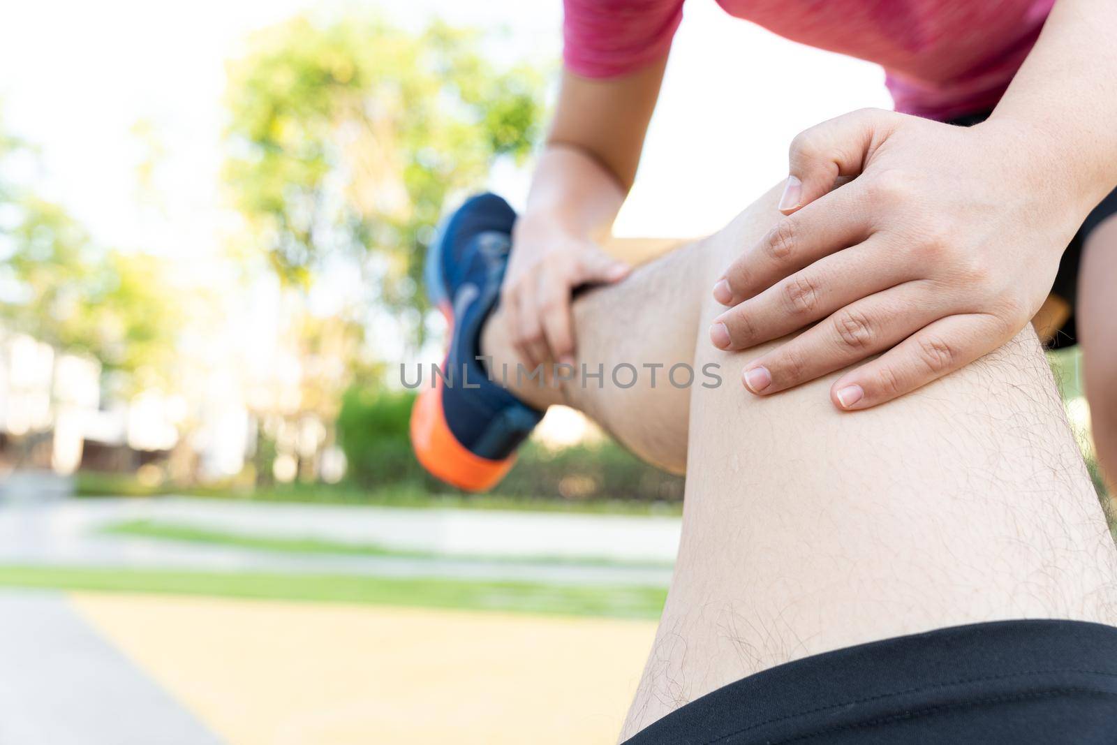 Female hand grab male leg to stretch after exercise injury.