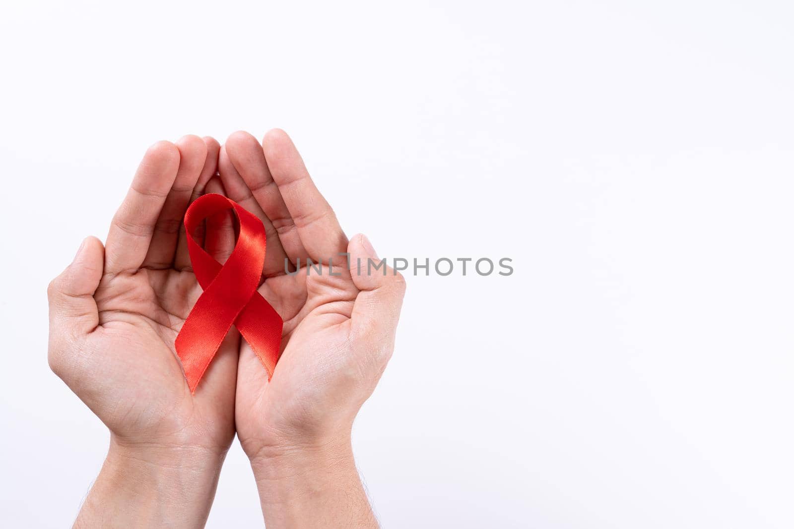 Aids awareness, man hands holding red ribbon on white background with copy space for text. World Aids Day, Healthcare and medical concept. by mikesaran