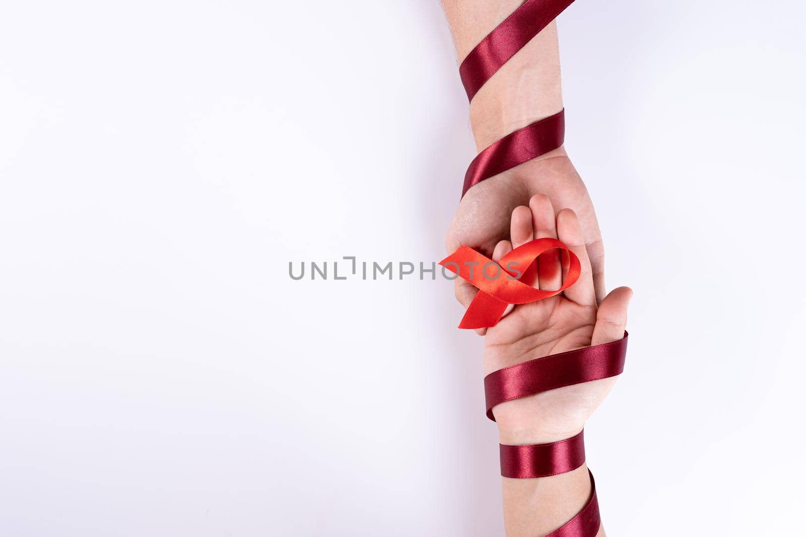 Aids awareness, man and woman hands holding red ribbon on white background with copy space for text. World Aids Day, Healthcare and medical concept. by mikesaran