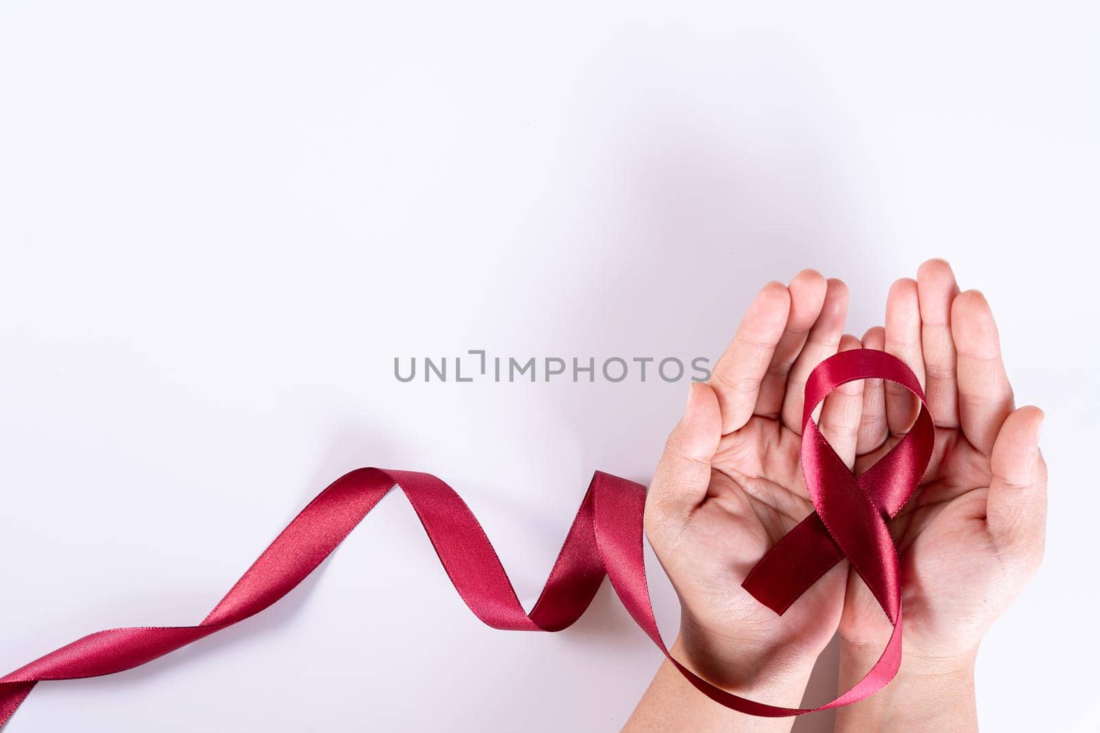 Aids awareness, woman hands holding red ribbon on white background with copy space for text. World Aids Day, Healthcare and medical concept. by mikesaran