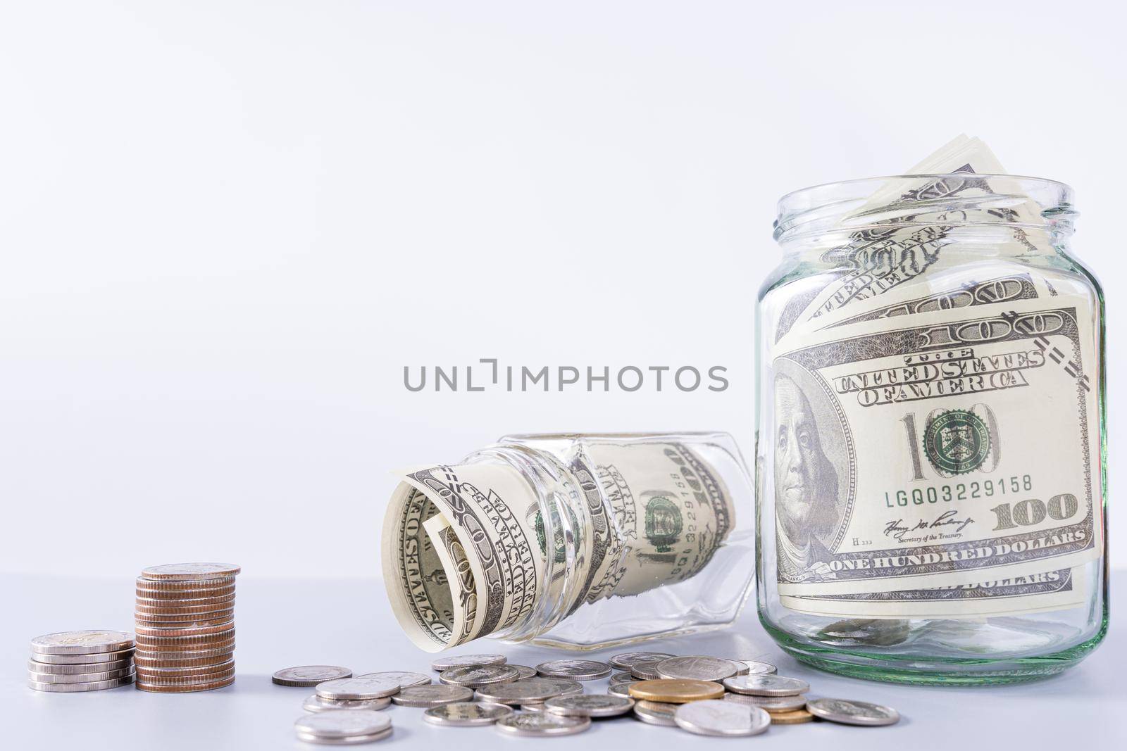 Money paper inside jar and stack coins isolated grey background. Property investment and house mortgage financial concept.