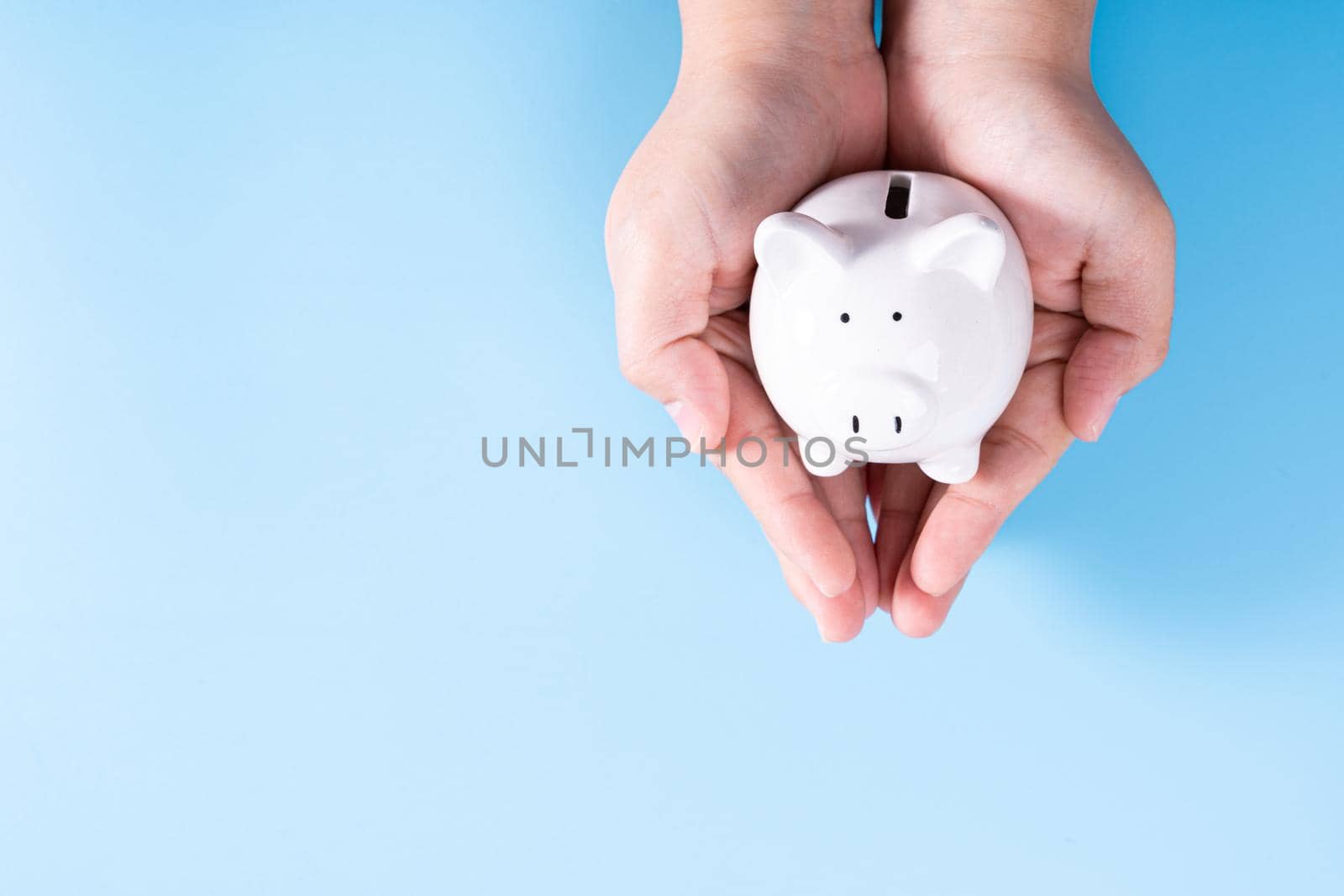 Hands hold a piggy bank isolated blue background. Saving money and investment concept.