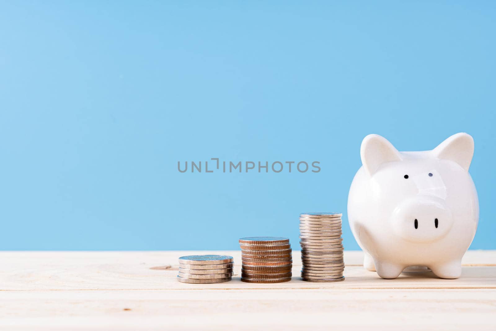 Piggy bank with stack coins isolated blue background. Saving money and investment concept.