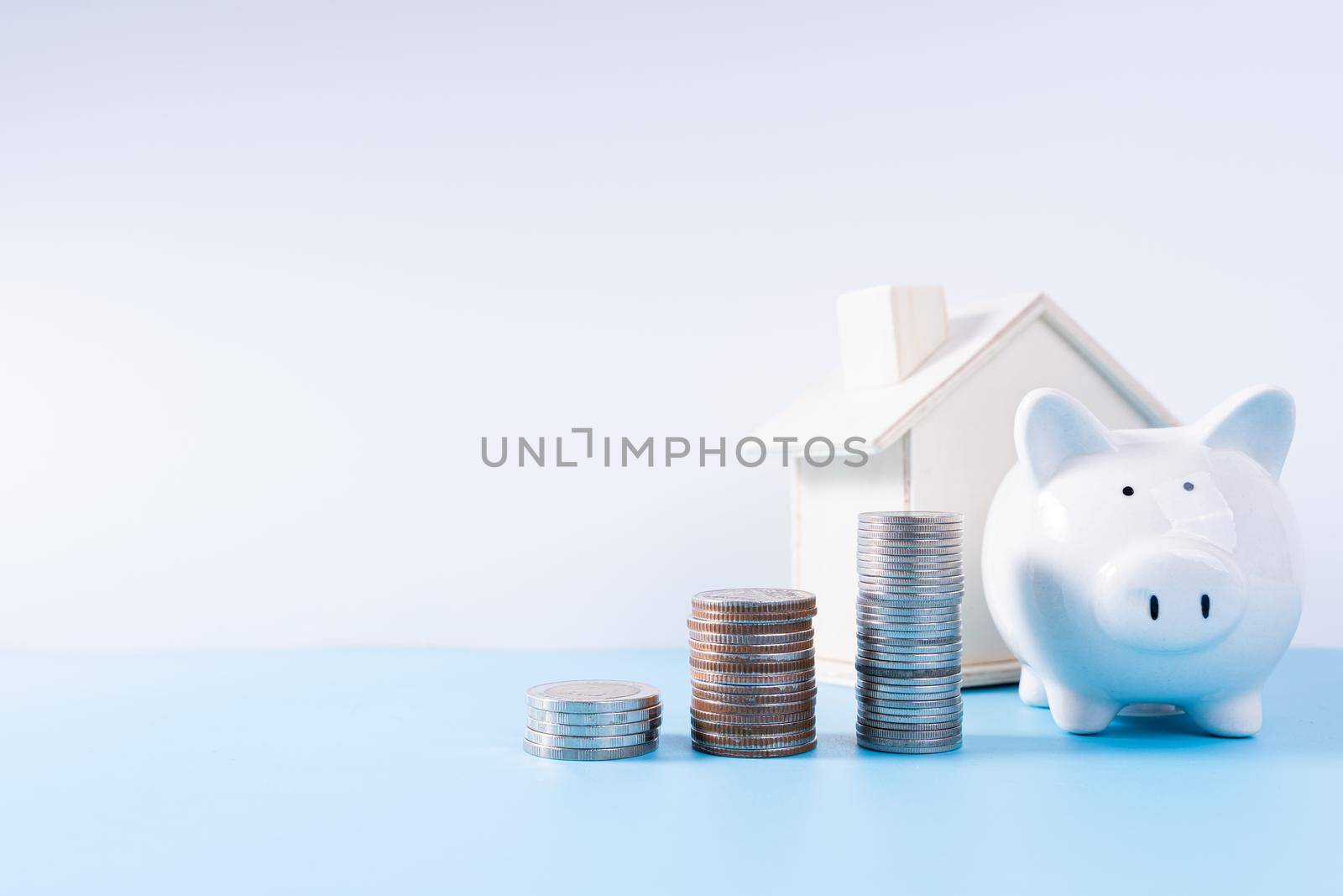 Piggy bank with wooden house and stack coins isolated grey background. Property investment and house mortgage financial concept. by mikesaran