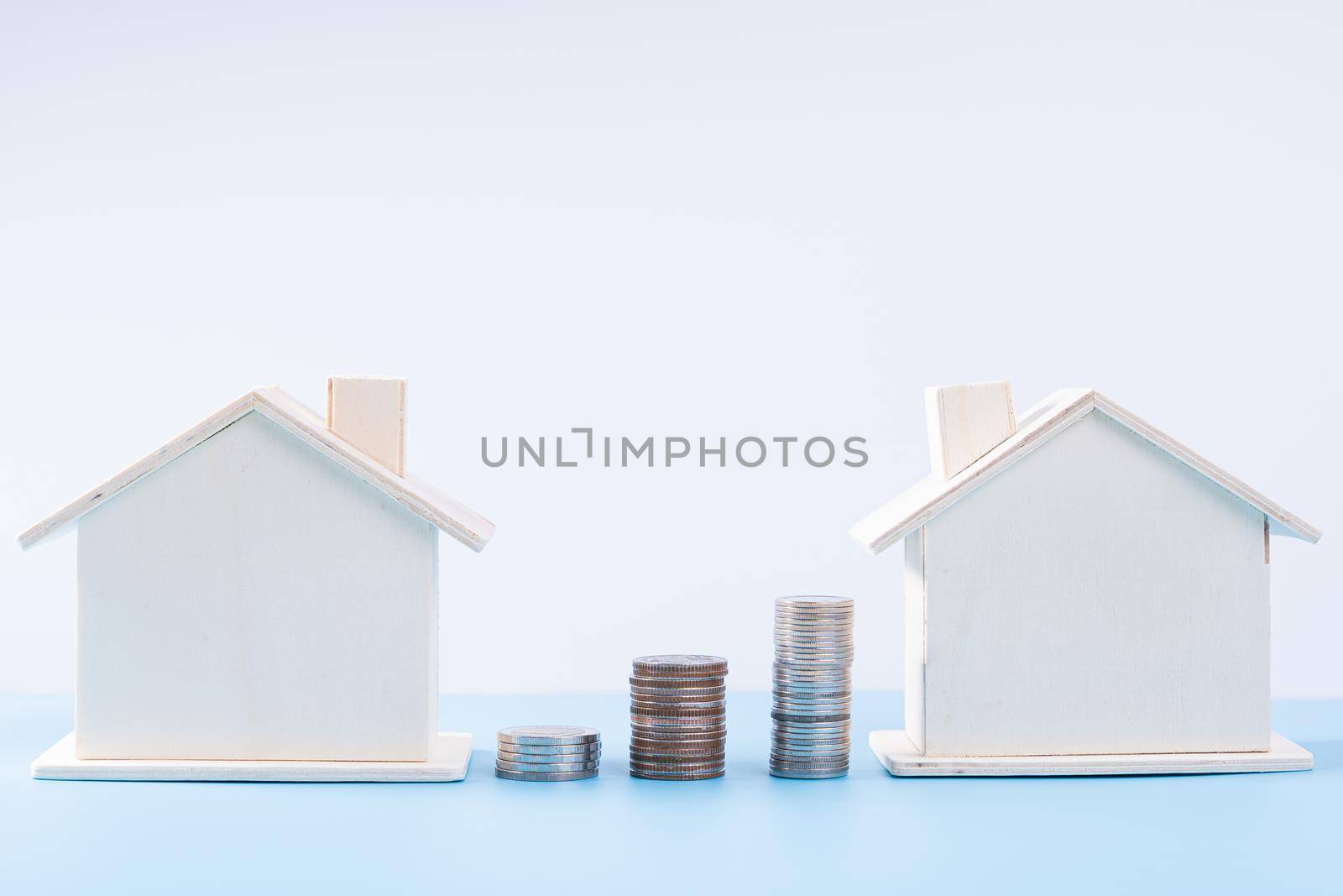 Wooden house with stack coins isolated grey background. Property investment and house mortgage financial concept.