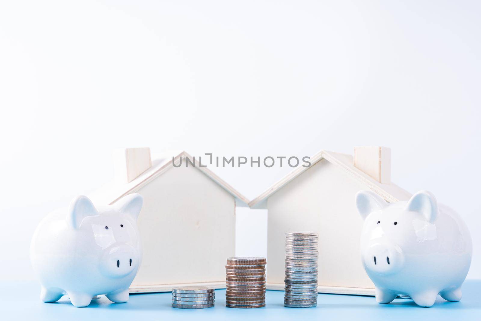 Piggy bank with wooden house and stack coins isolated grey background. Property investment and house mortgage financial concept.