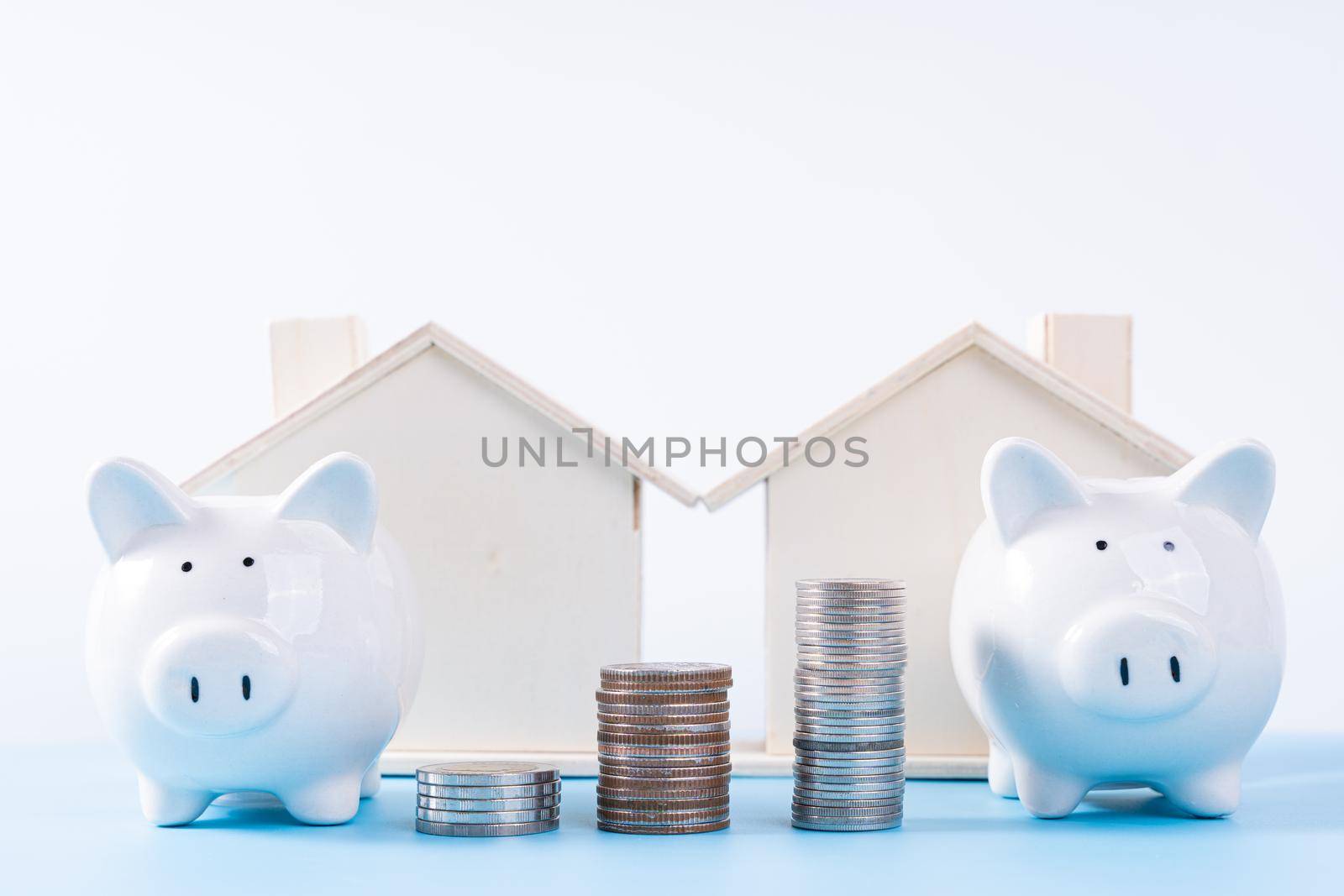 Piggy bank with wooden house and stack coins isolated grey background. Property investment and house mortgage financial concept.
