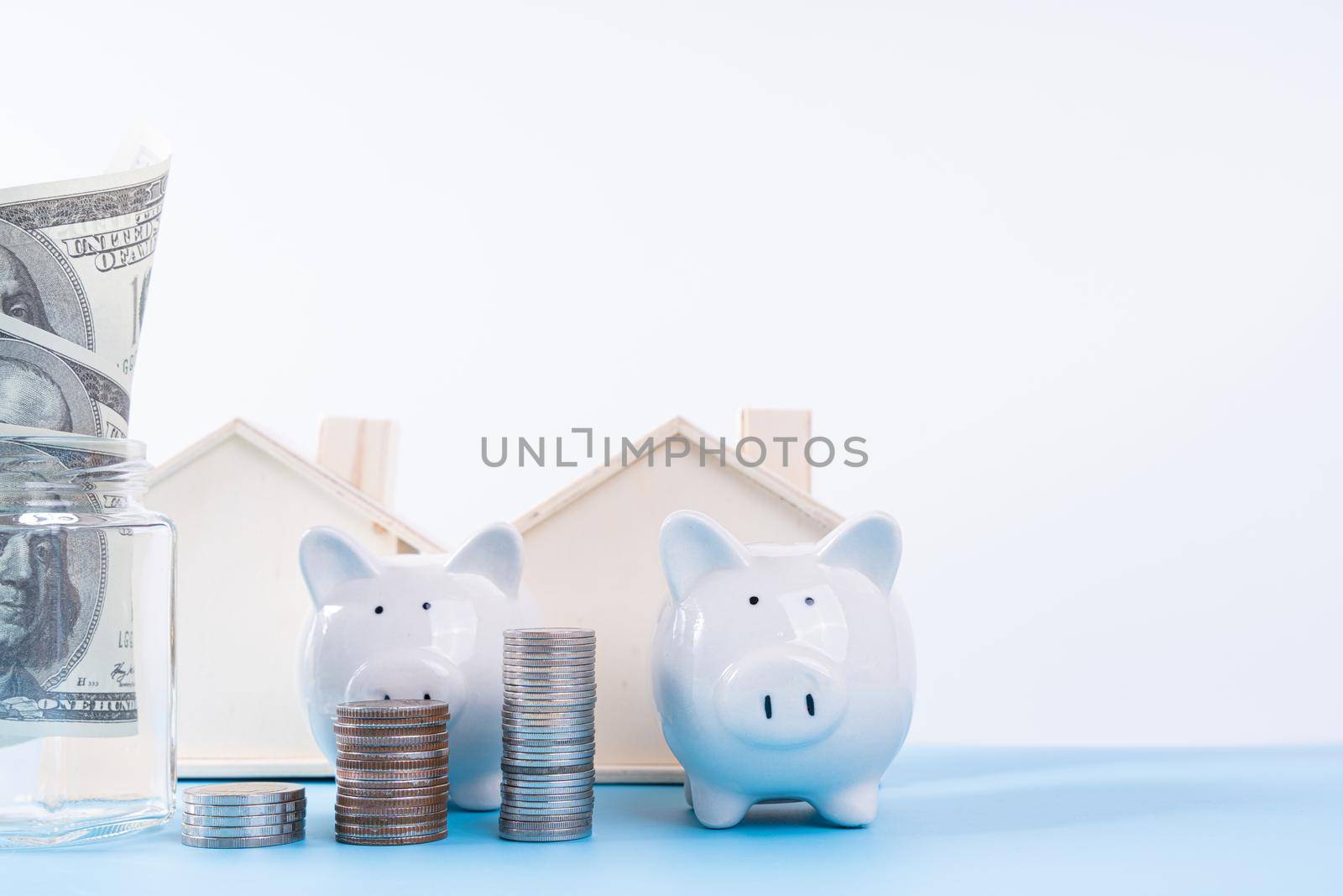 Piggy bank with wooden house and stack coins isolated grey background. Property investment and house mortgage financial concept.