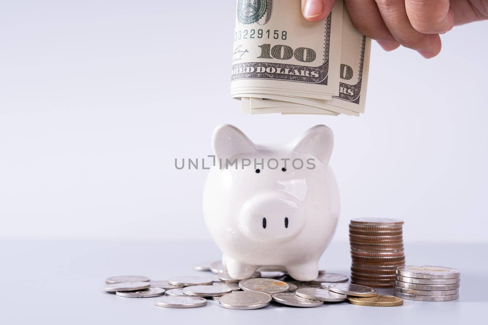 Hand putting money paper into piggy bank with stack coins isolated grey background. Saving money and investment concept.