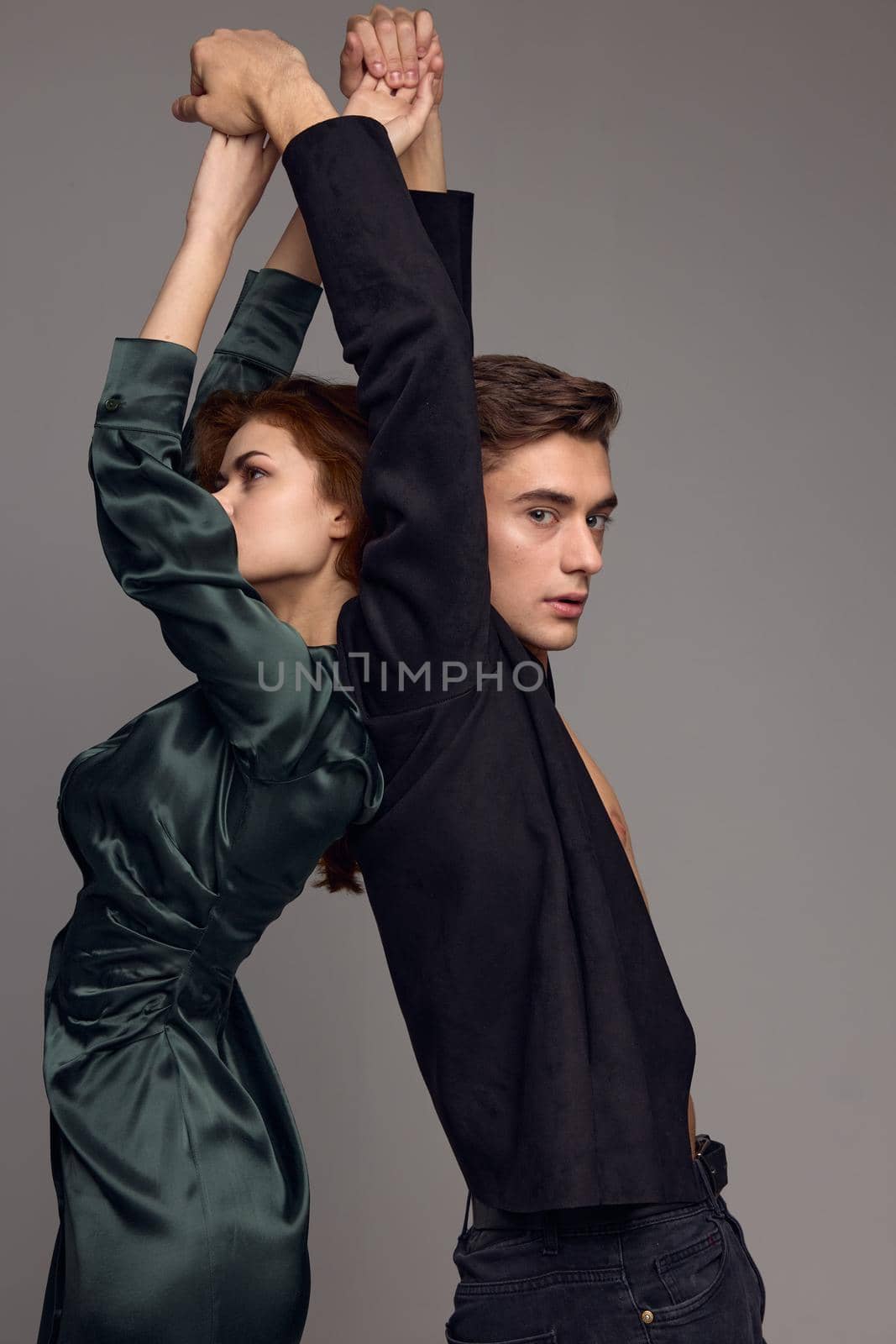 A man in a suit and a woman in an evening dress Standing with their backs to each other with their hands up. High quality photo
