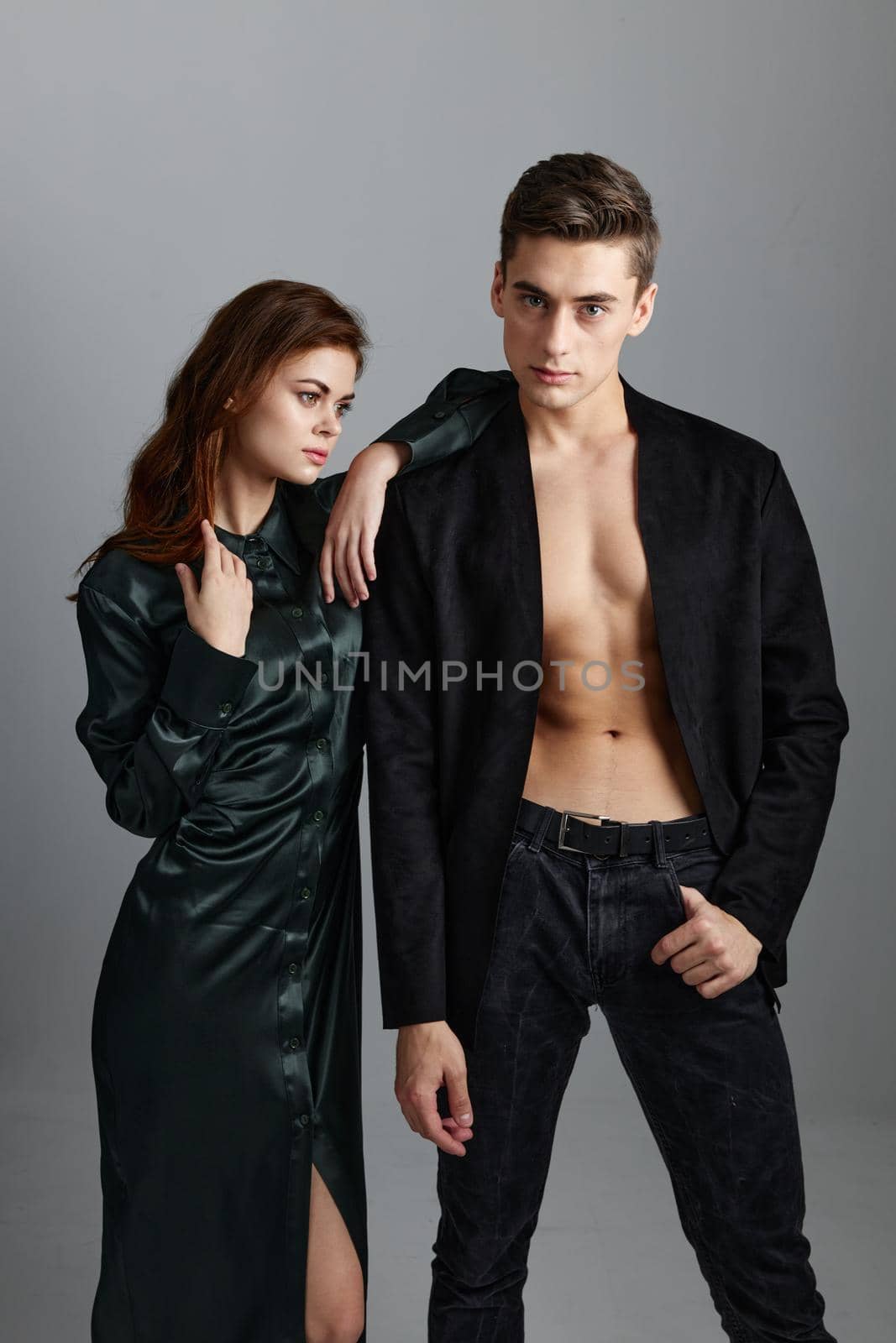A man in a jacket and trousers stands next to a woman on a gray background cropped view. High quality photo