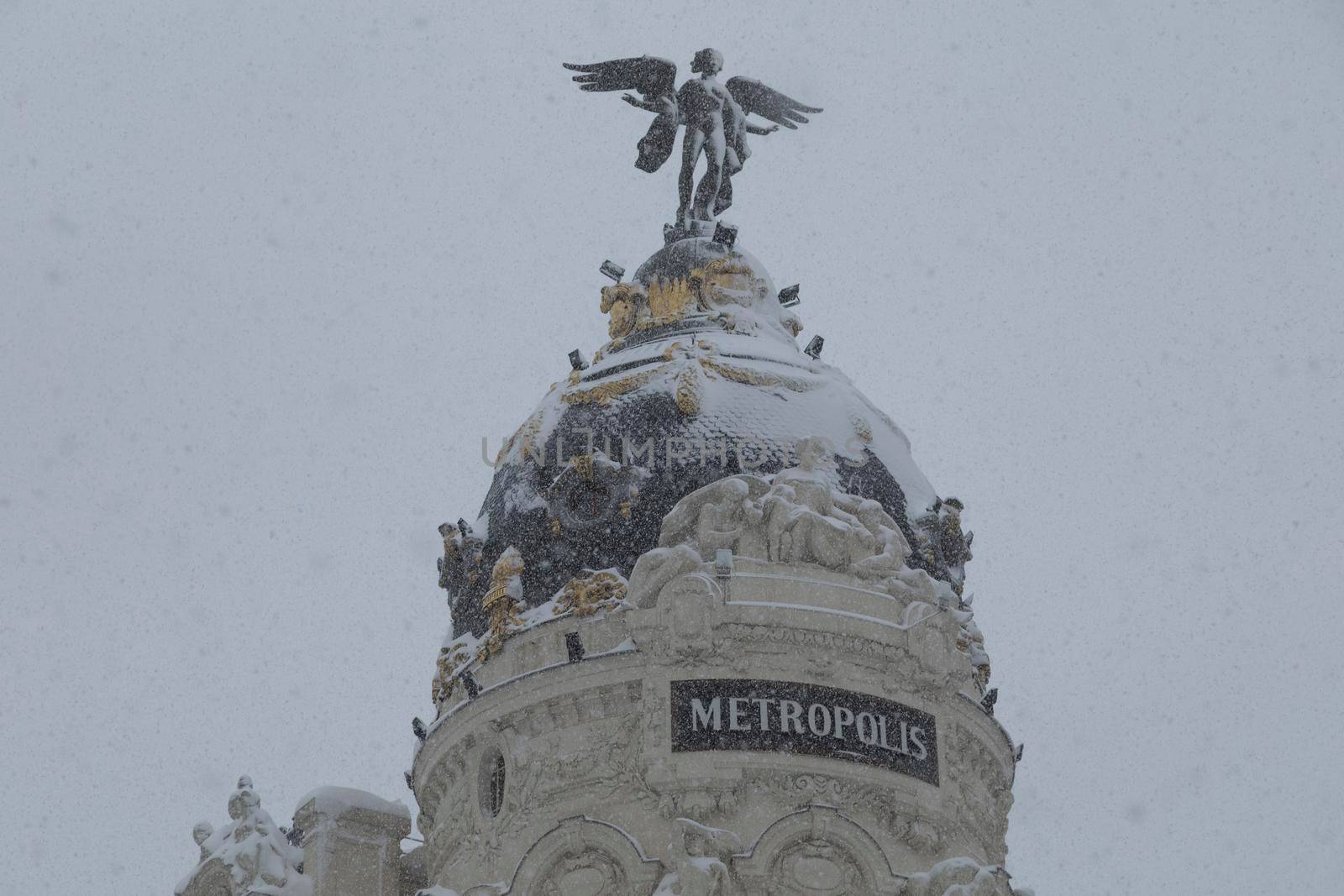 Madrid, Spain - January 09, 2021: Famous Metropolis building between Calle Alcala and Gran Via, on a snowy day, due to the Filomena polar cold front.