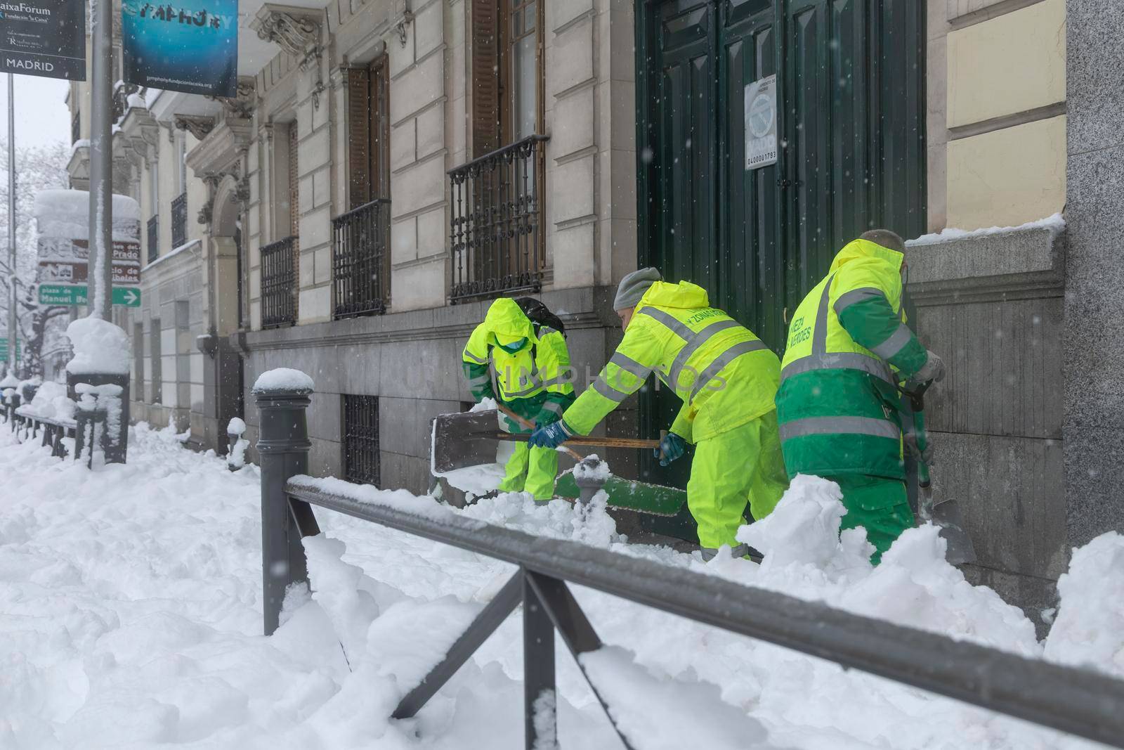 Madrid, Spain - January 09, 2021: A group of workers from the municipal cleaning service work cleaning the sidewalks with shovels and salt, due to the filomena polar cold front.