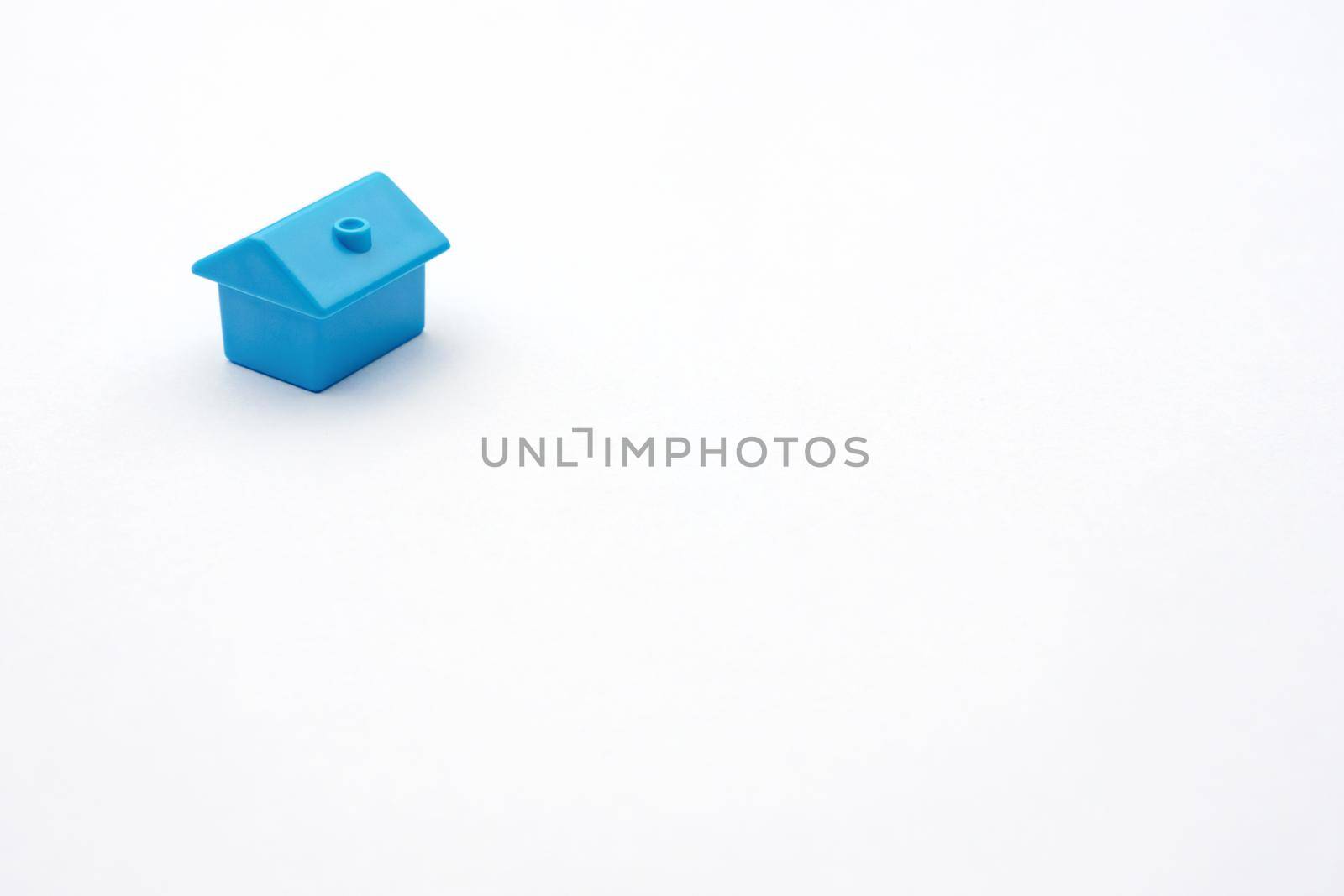 Simply minimal design one single blue toy miniature or model cottage house on white background and copy space. Purchasing or buying eco house or rental of property and constructing new small cosy home