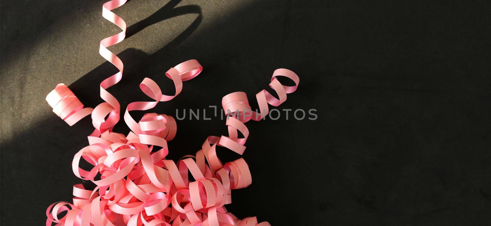 Pink serpentine streamer on black background Party accessory