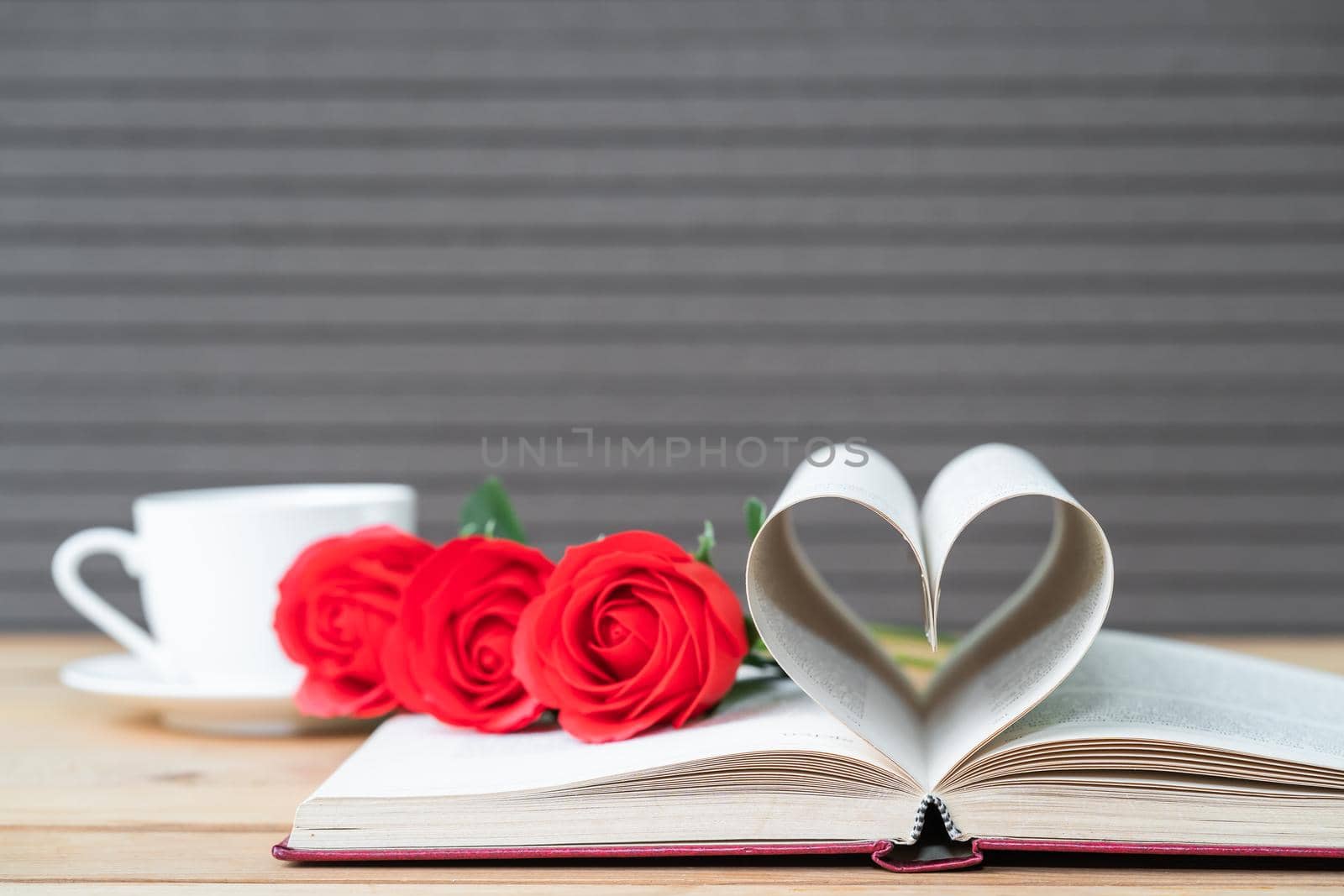 Page of book curved into a heart shape and red rose Love concept of heart shape from book pages and coffee cup