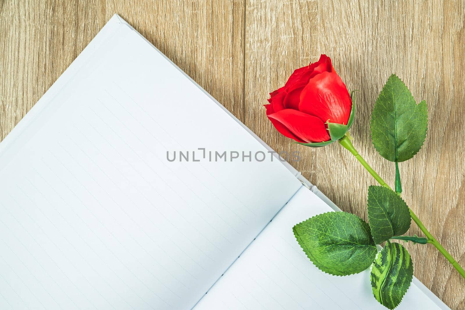 Top view shot of  empty blank notebook diary and red roses on wood table,Valentine concept