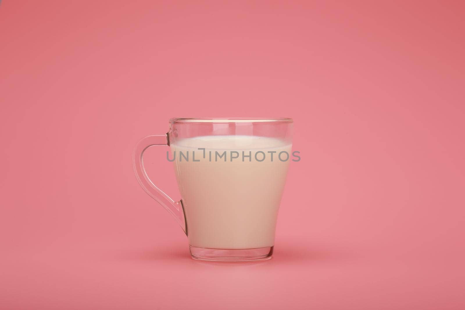 Transparent cup with milk against pink background with copy space by Senorina_Irina