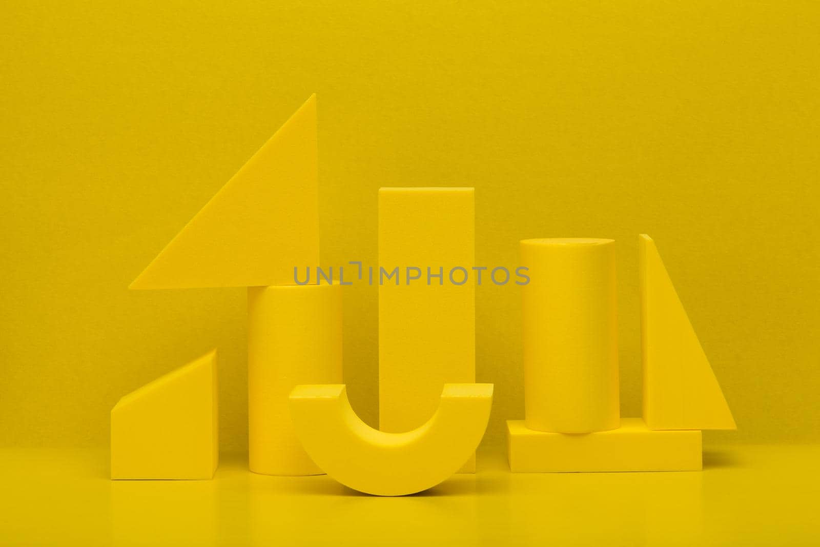 Abstract monochromatic composition with yellow geometric figures against yellow background. High quality photo