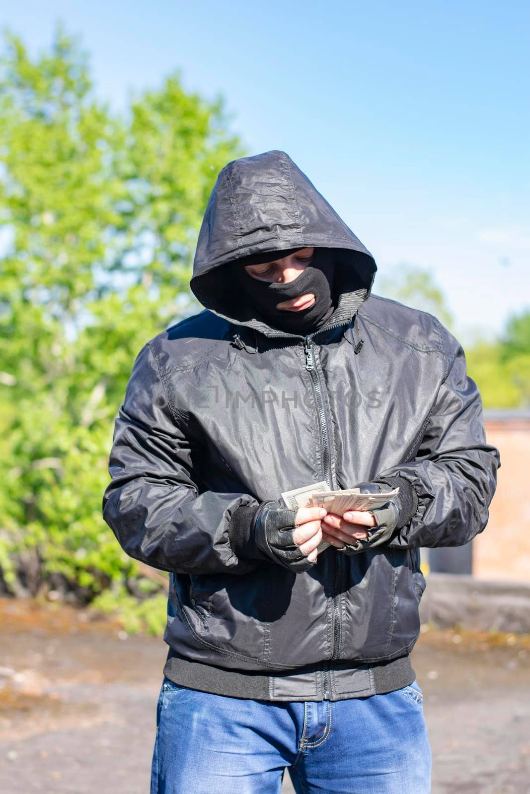 the bandit, inclining his head impudently, stands and considers the illegally obtained money in a criminal way