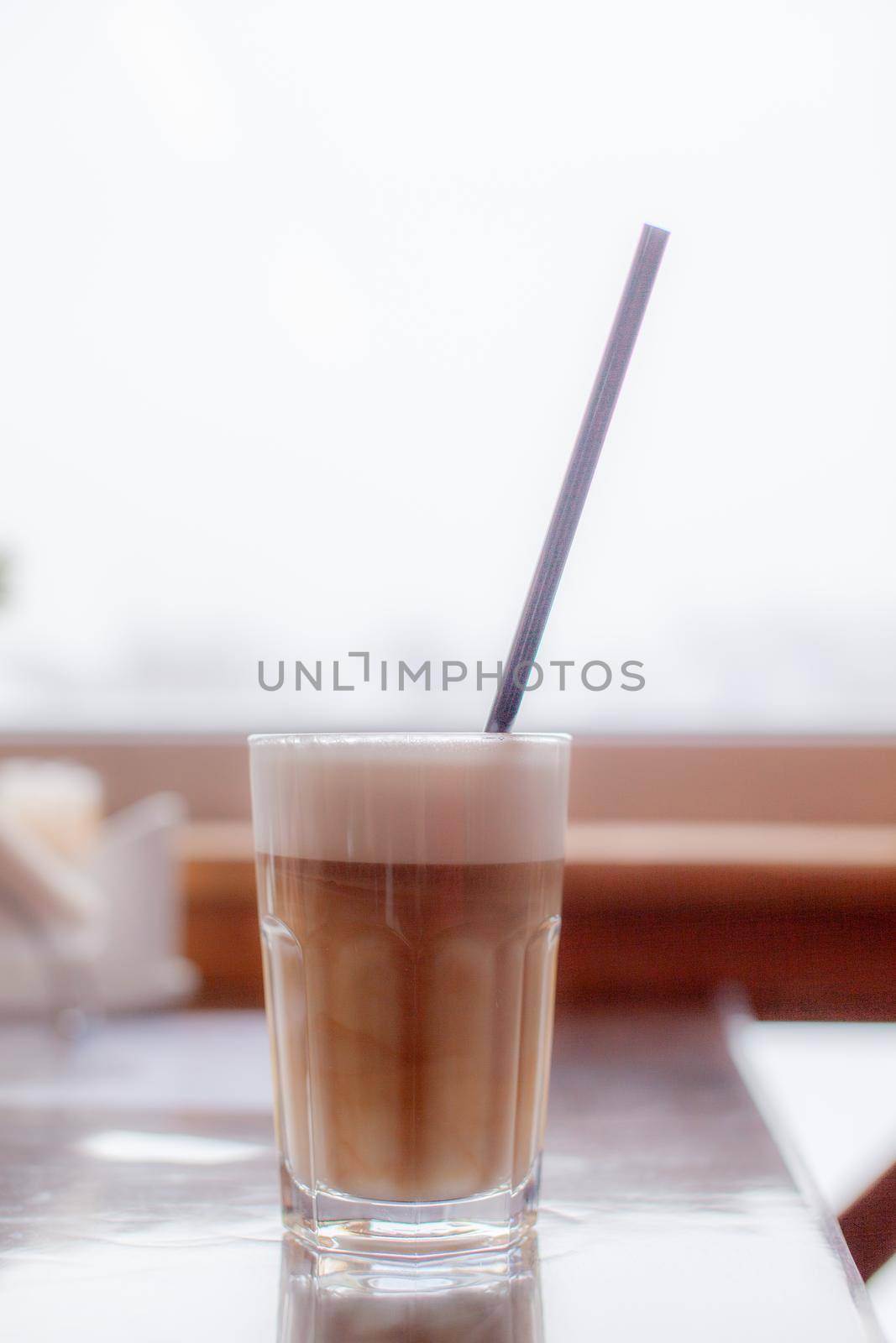 Hot Latte coffee in a glass and a fresh apple dessert next to it. The hot drink is served with a plastic straw. Delicious breakfast in the cafe