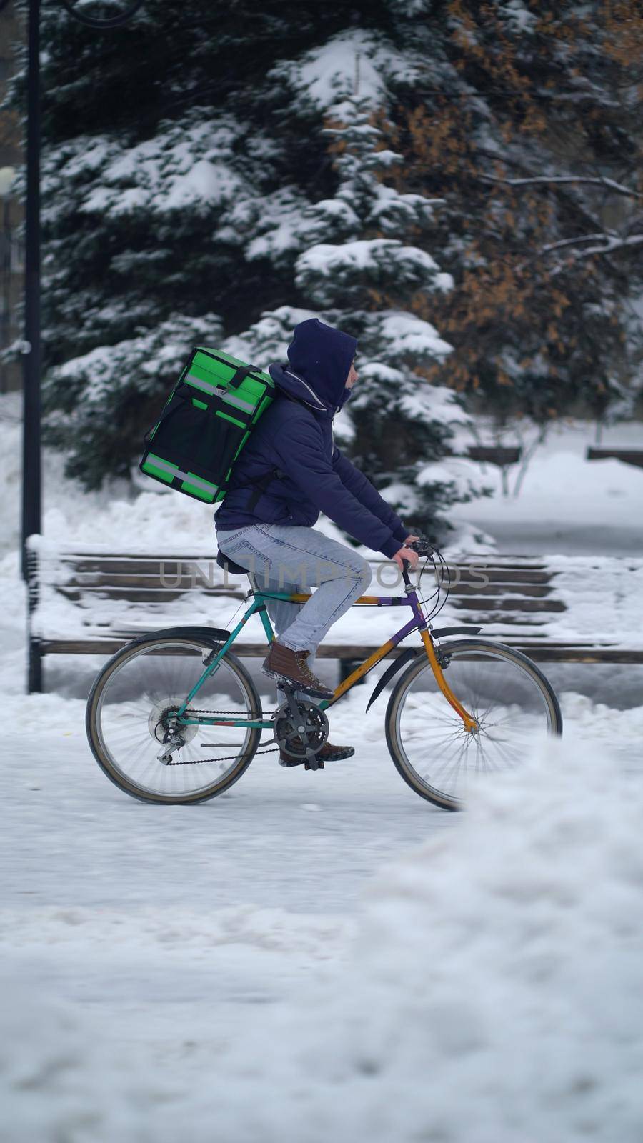 Courier is delivering food with backpack at winter.