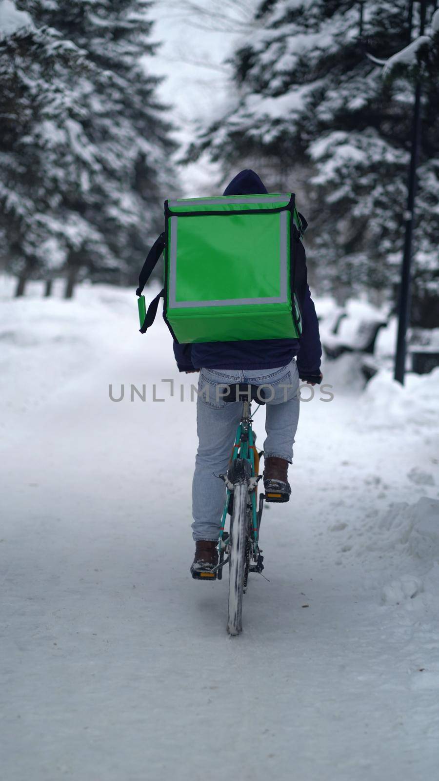 Courier is delivering food with backpack at winter.