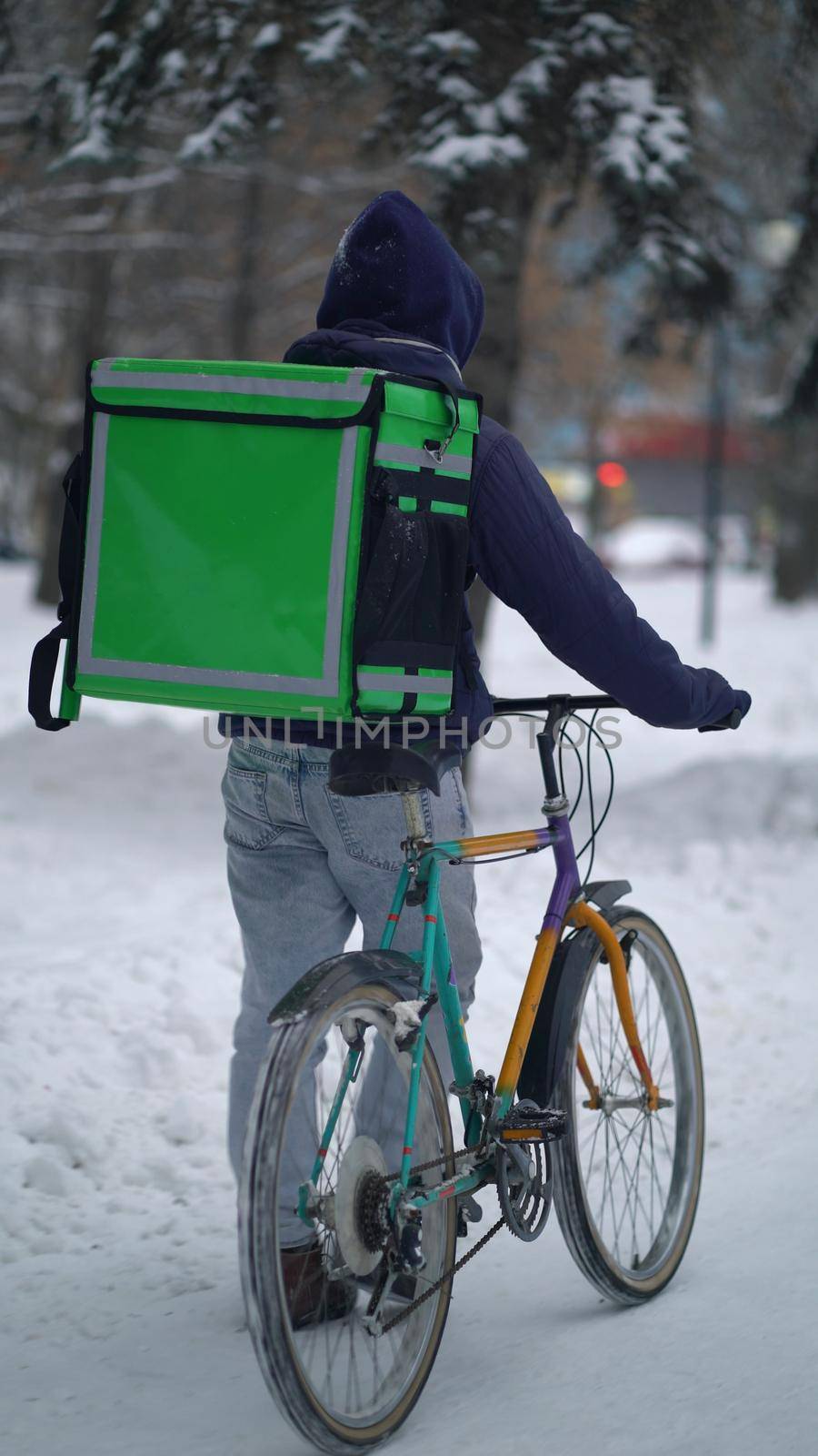 Courier is delivering food with backpack at winter.