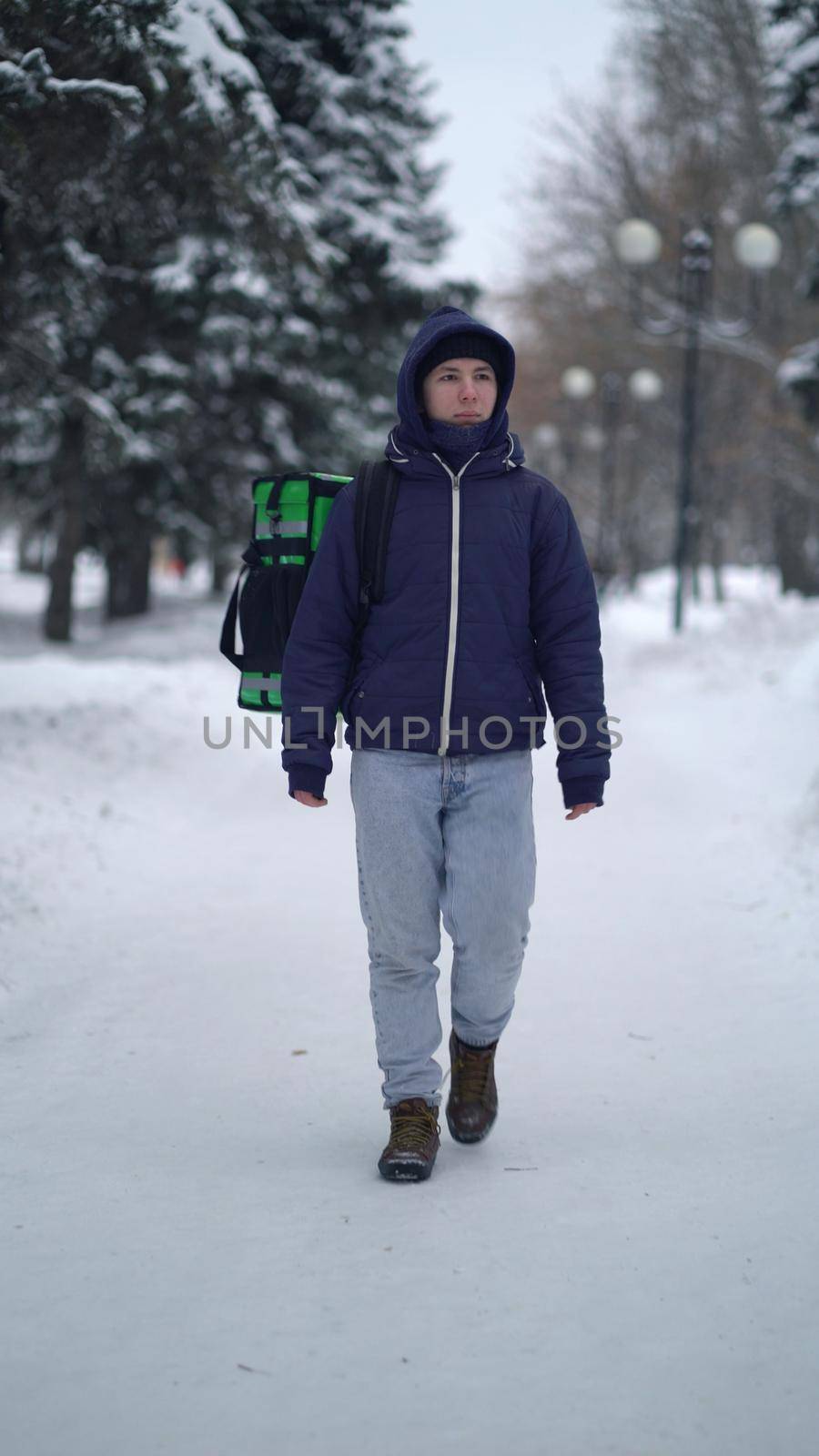 Courier is delivering food with backpack at winter.