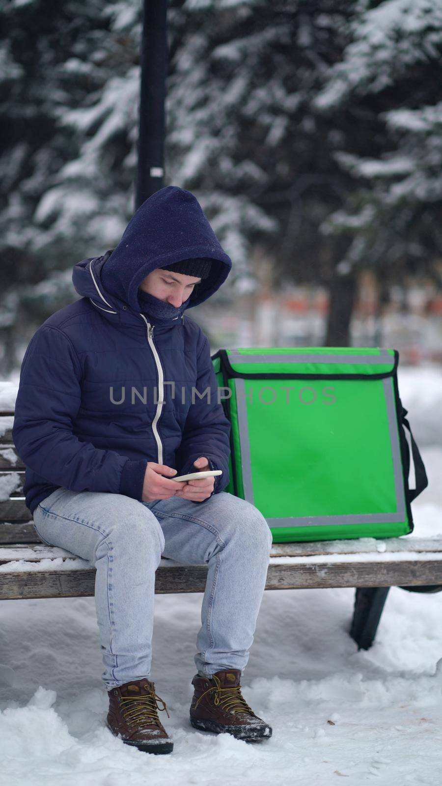 delivery boy with an insulated backpack looking for the client's address in the delivery app.