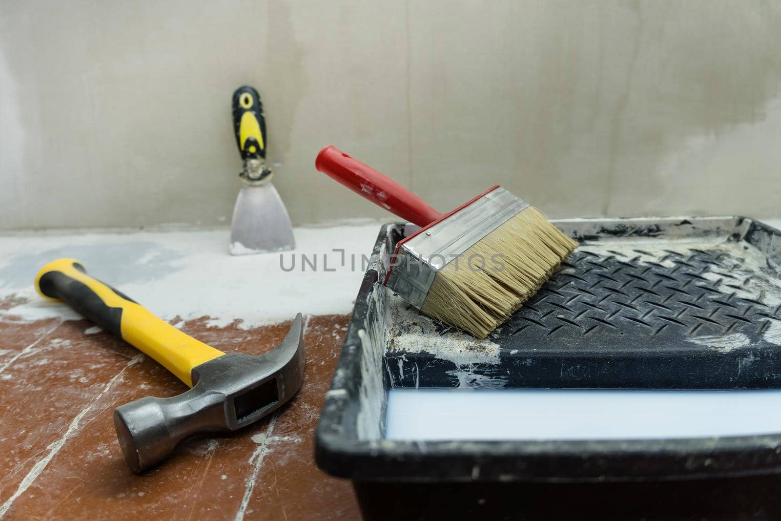 Construction and painting tools lie on the floor during the repair and restoration of the house.Work as a Builder or handyman in the house.Finishing or repairing a room.Job of repairing the apartment