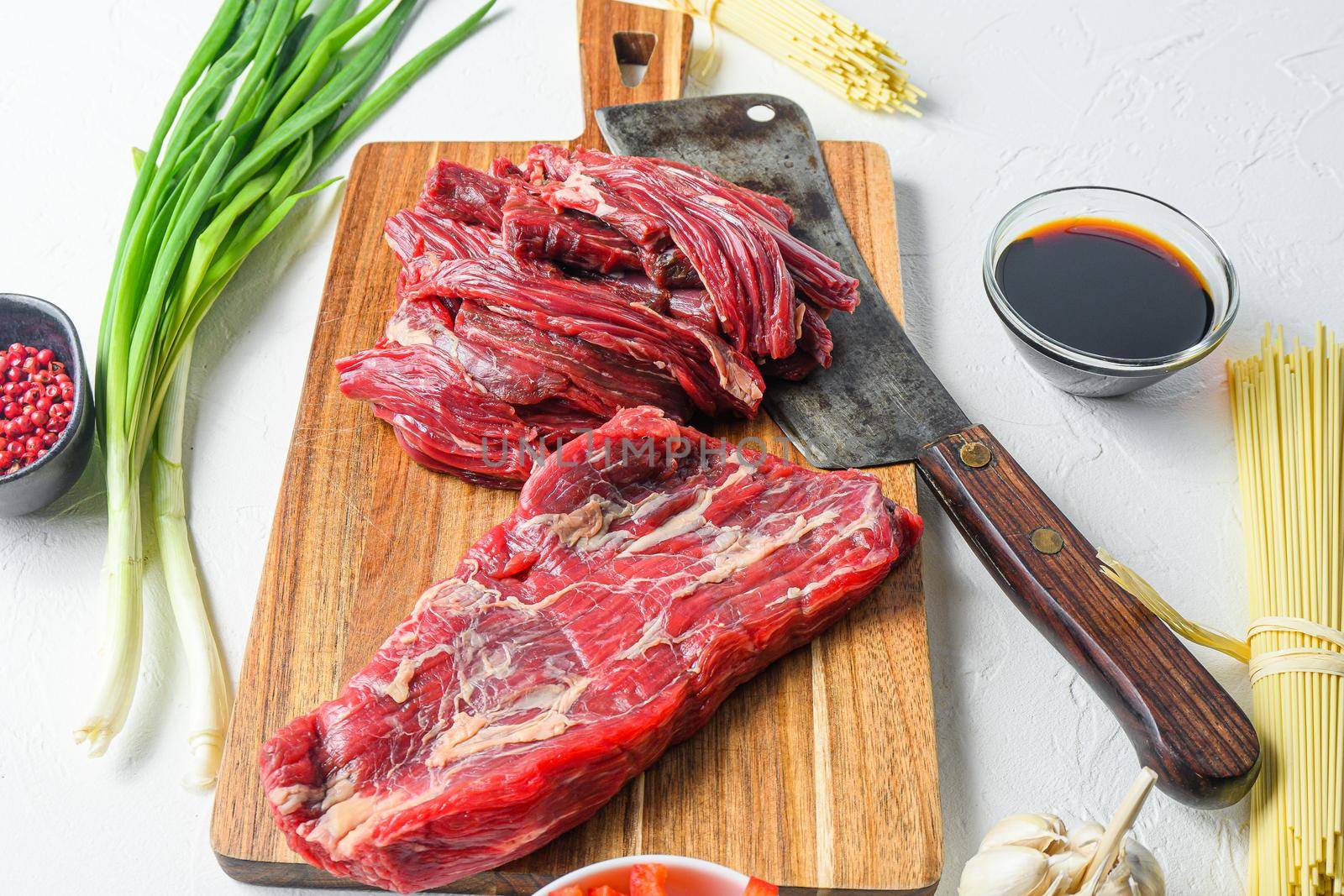 Cooking ingredients for making Homemade stir fry noodles with beef steak. Side view on white concrete table. by Ilianesolenyi