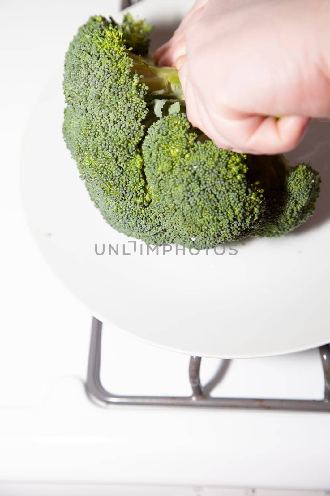 Woman's hands chopping a fresh crown of broccoli