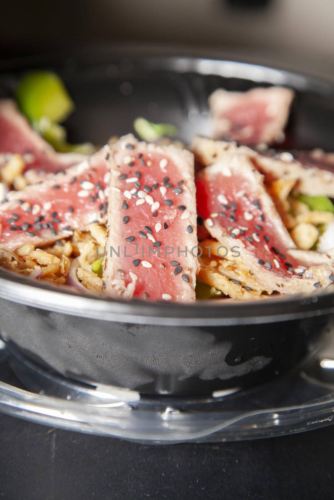 Seared tuna salad with lettuce, sliced green bell pepper, and red onion on a wooden table