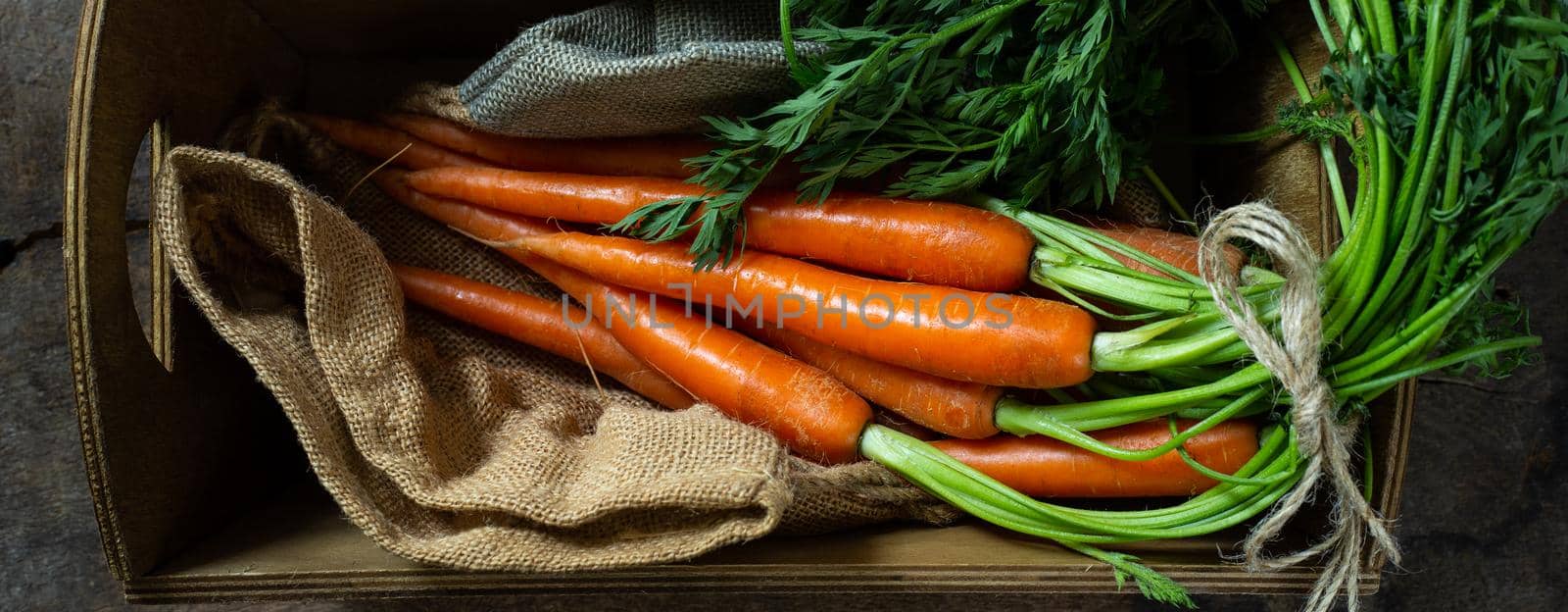 Fresh carrots on rustic kitchen with canvas bag and wooden box. Flat lay, top view