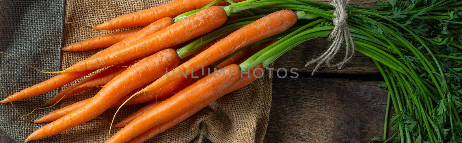 freshly picked vegetables carrots. Bunch of fresh carrots on canvas bag on old wood background. Rustic kitchen, horizontal flat lay