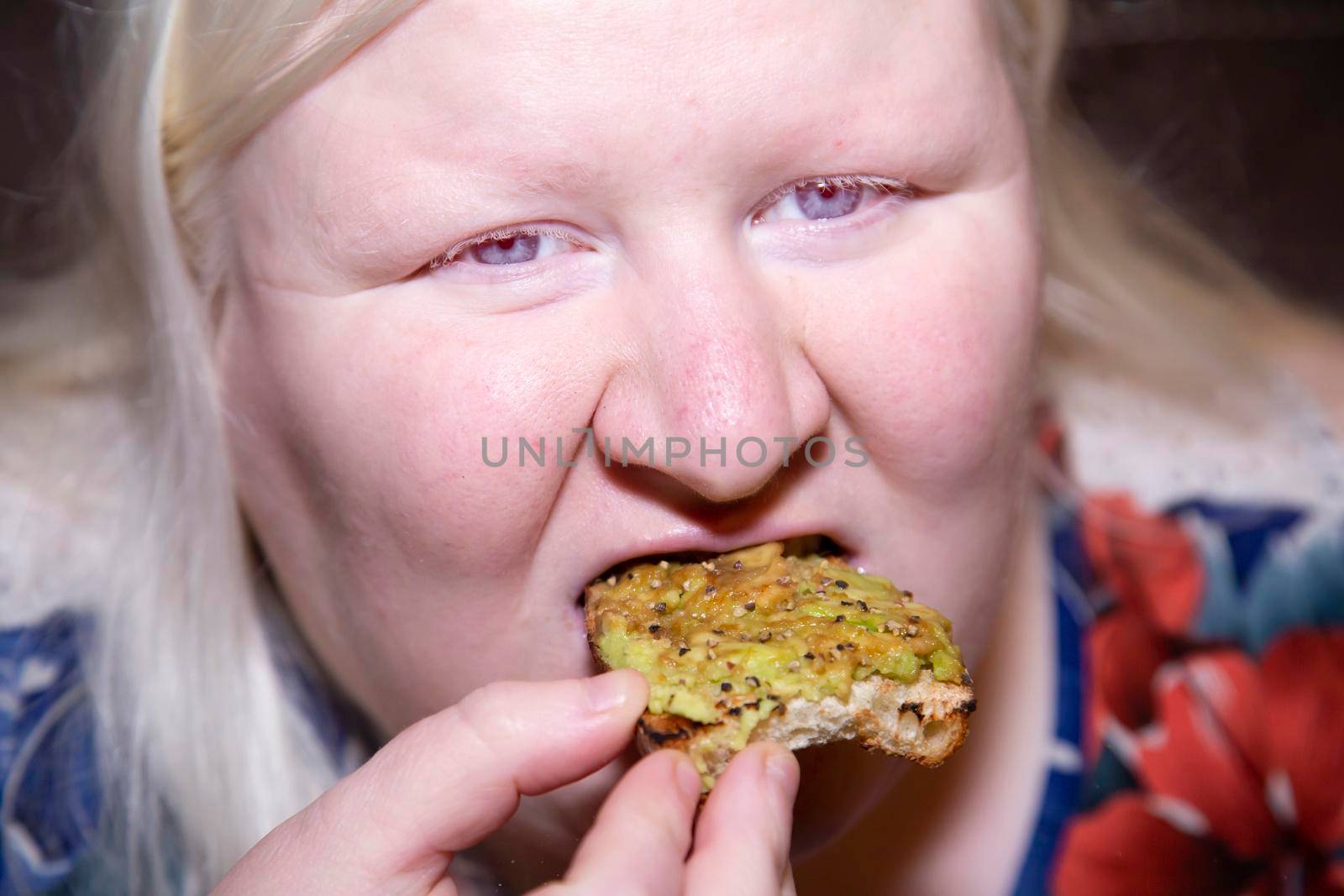 Woman happily eating a piece of avocado toast
