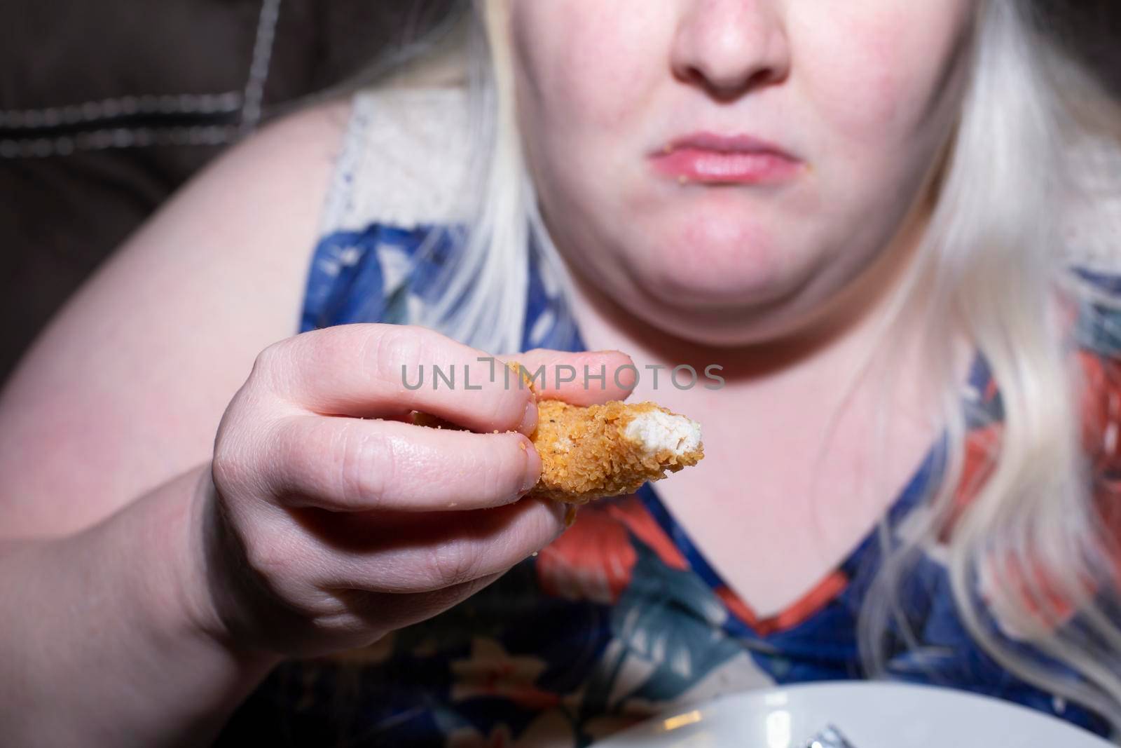 Obese, albino woman eating a fried chicken tender