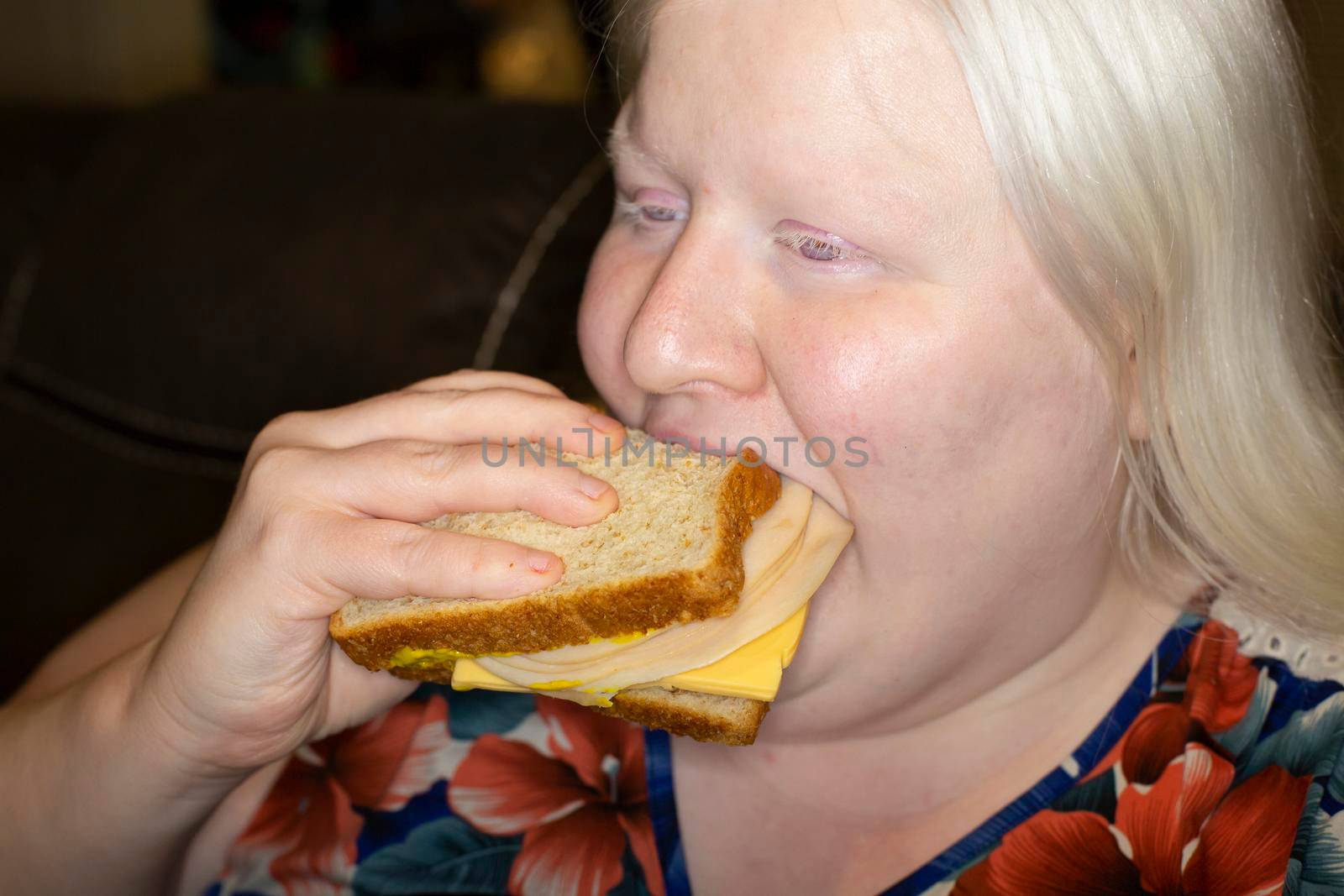 Woman eating a lopsided chicken and cheese sandwich