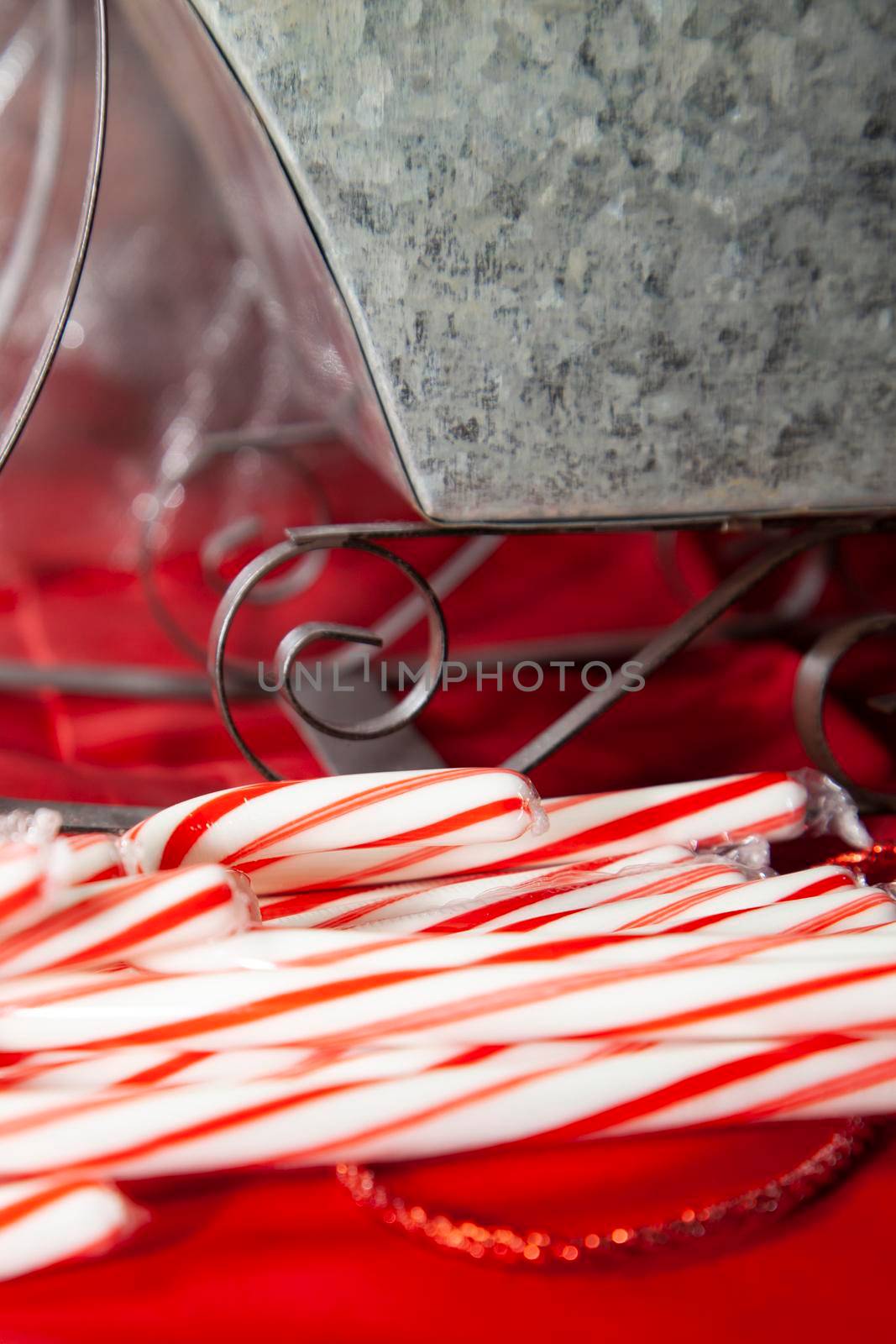 Candy canes on a red, Christmas background with a tin sleigh in the background