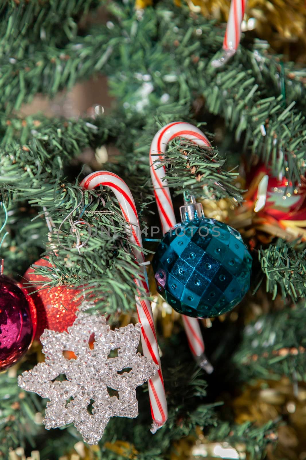 Two candy canes on an artificial Christmas tree near purple, red, blue, and clear decorations