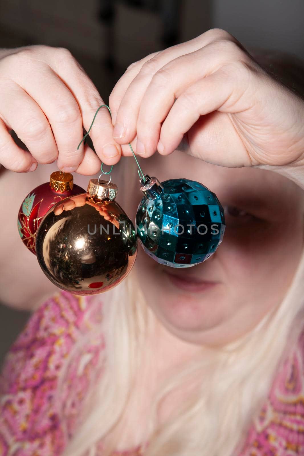 Woman preparing to hang red, gold, and blue globes for the holidays