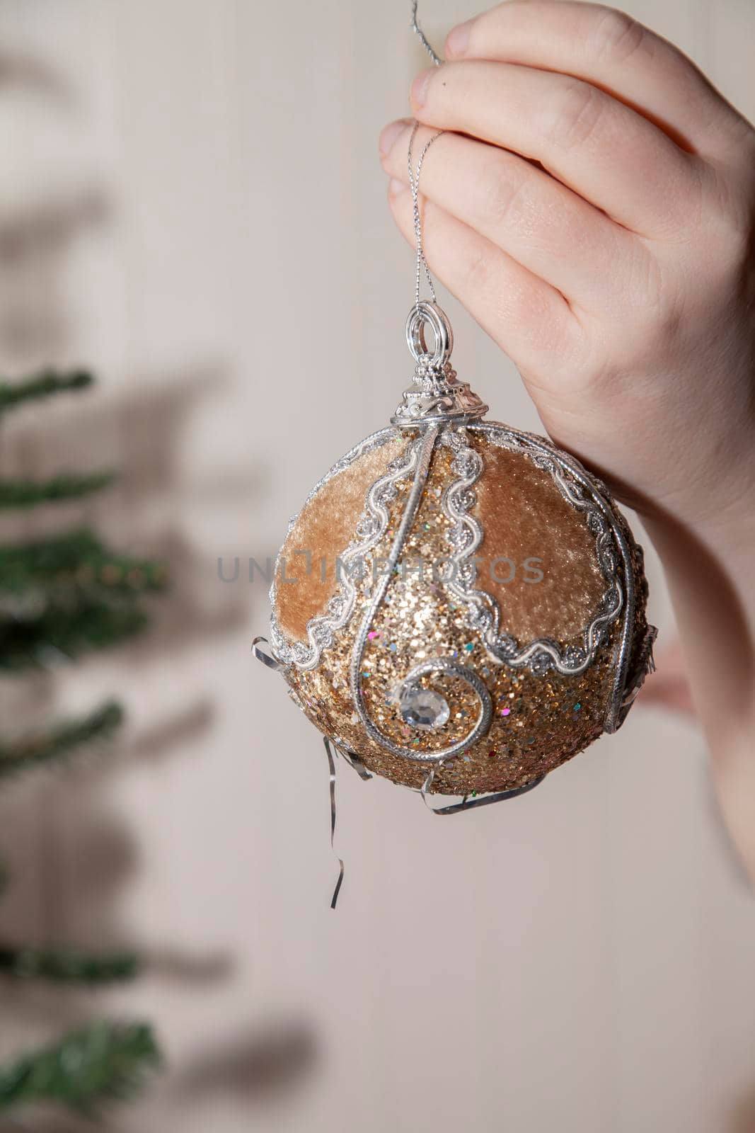 Woman preparing to hang a fuzzy, tan Christmas ornament